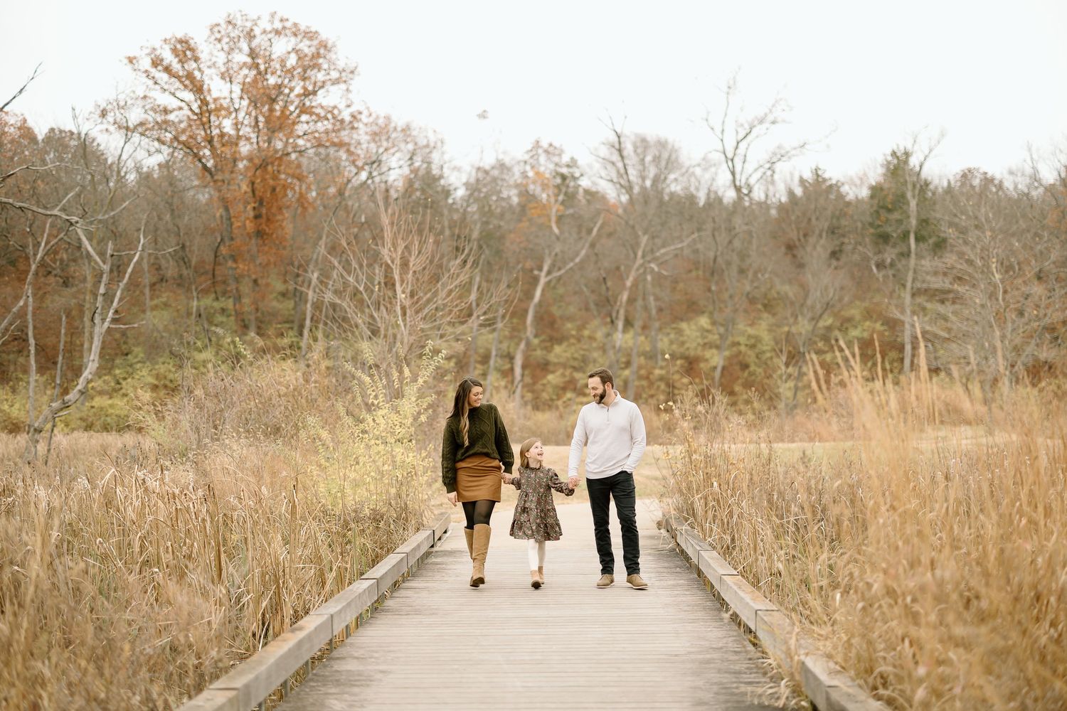 Couple walking together on wooden path through autumn landscape.