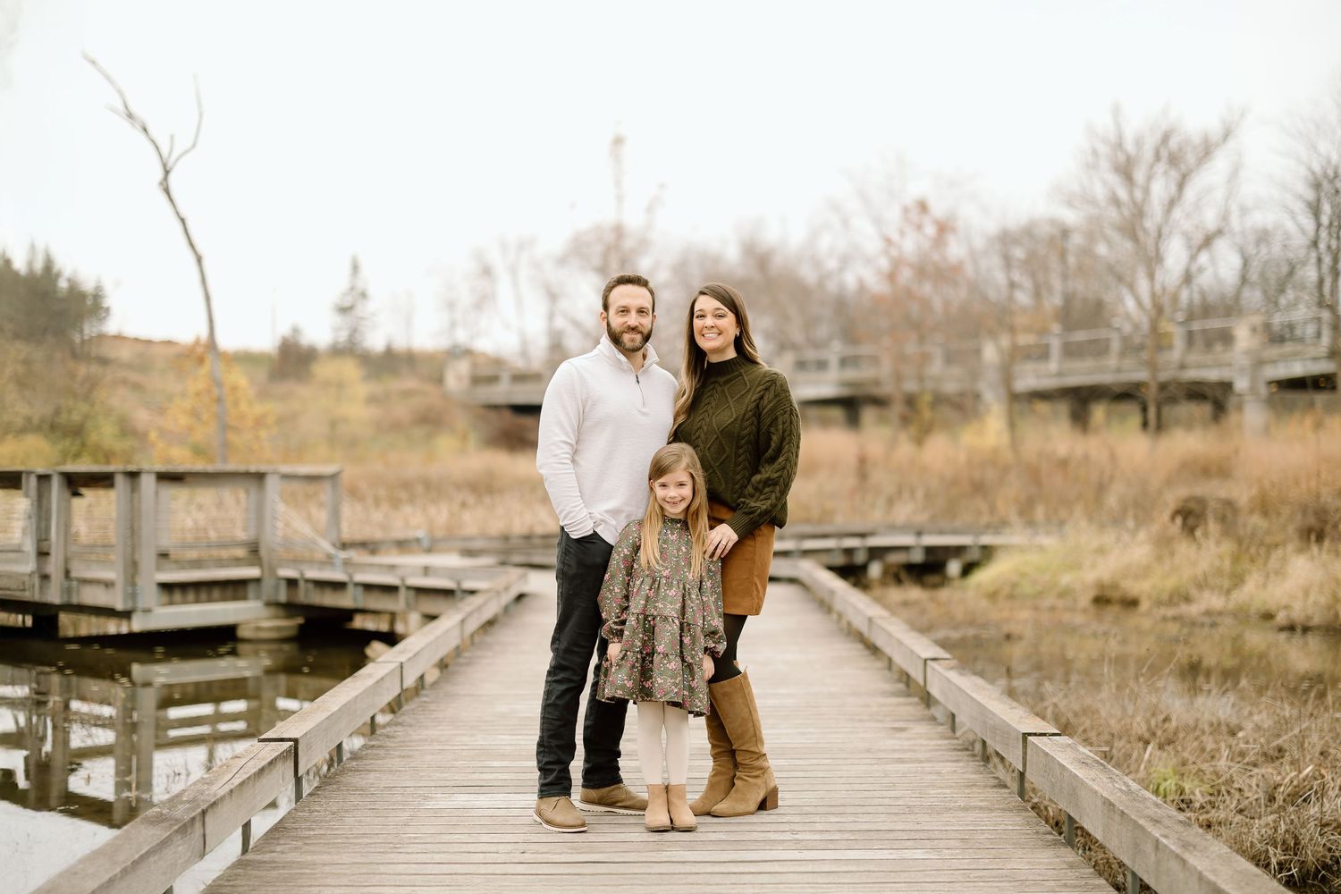 Family standing together on wooden walkway surrounded by fall foliage.