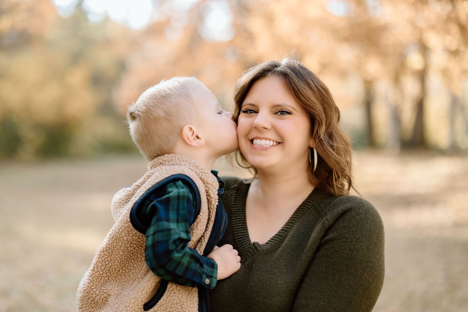 A sweet moment captures a child giving a kiss during an outdoor family portrait session.