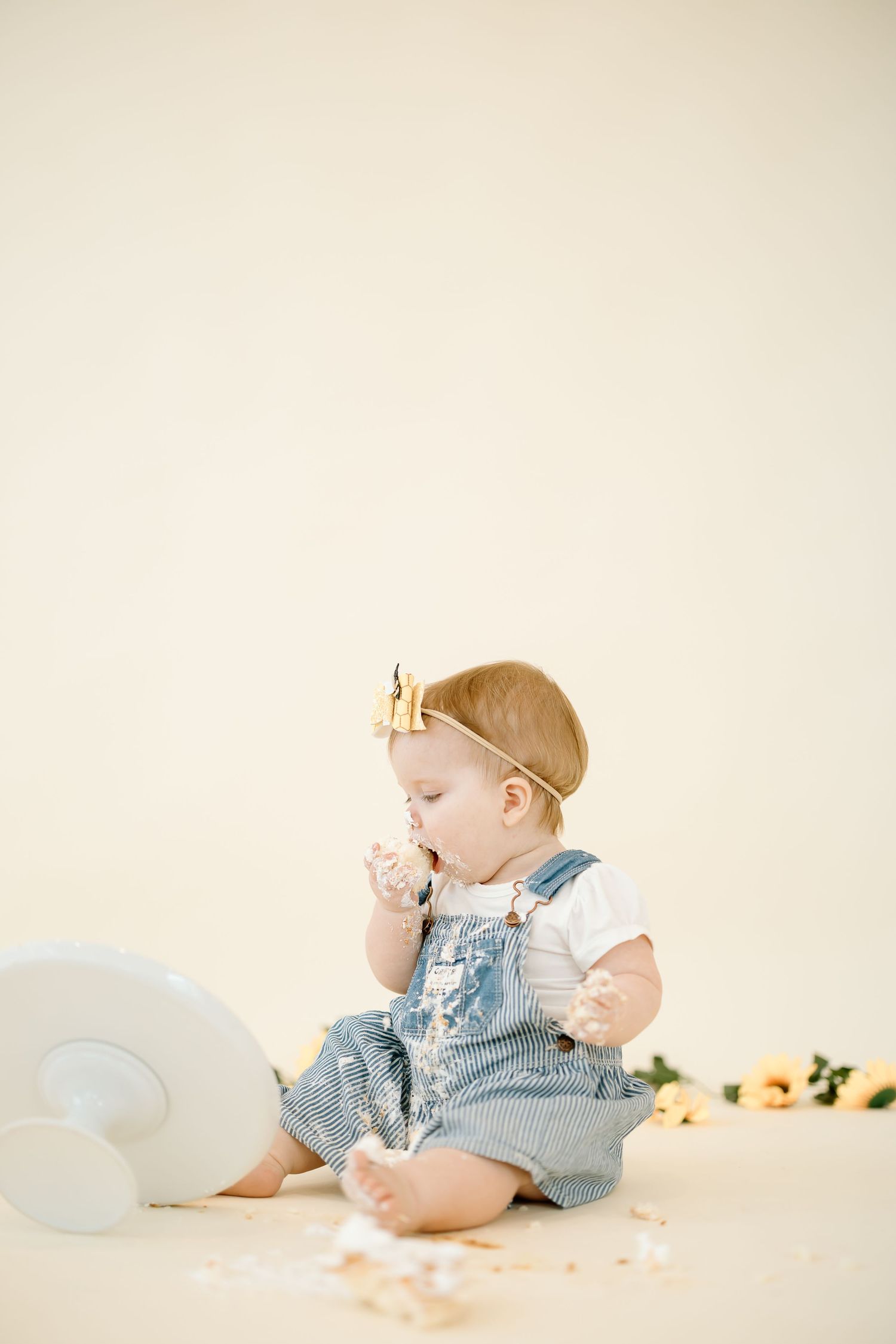 Baby wearing denim romper lies on white backdrop in sequence of candid poses during professional photo session.