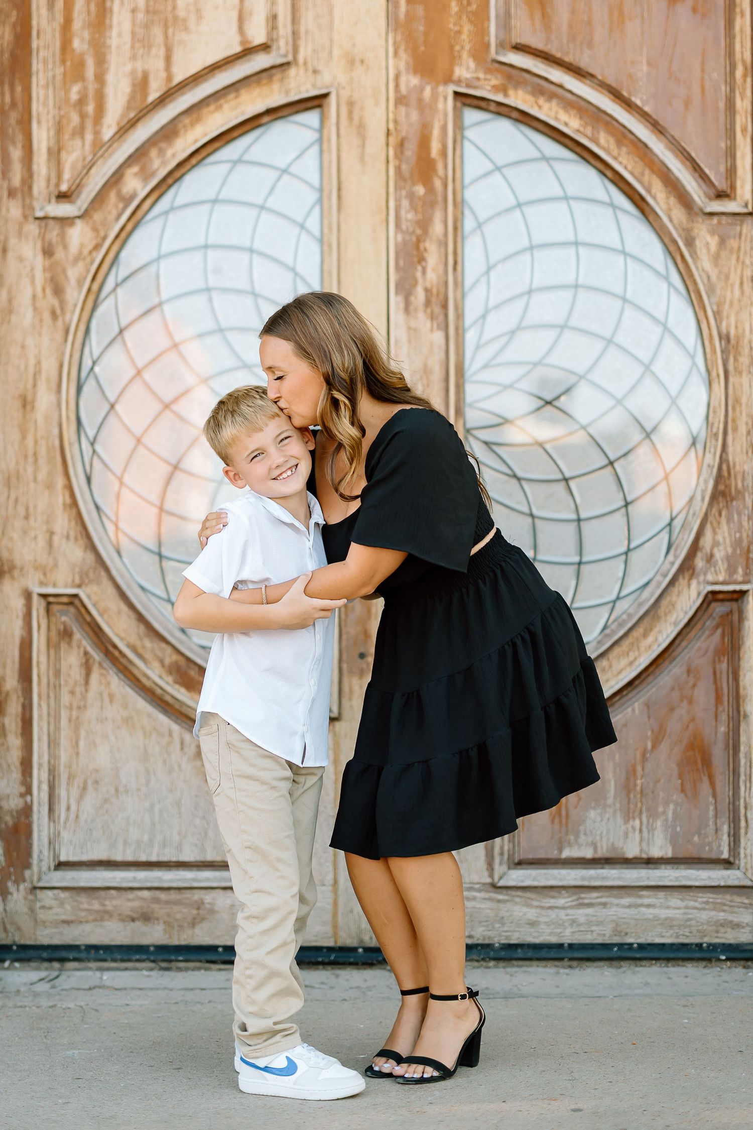 A tender moment captured between two people in front of a decorative door with circular glass panels.