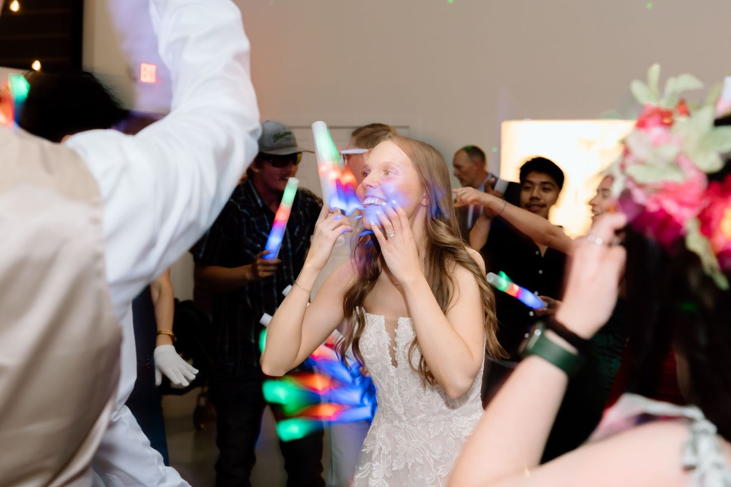 Bride dancing joyfully with glowing LED sticks at a lively wedding reception party.