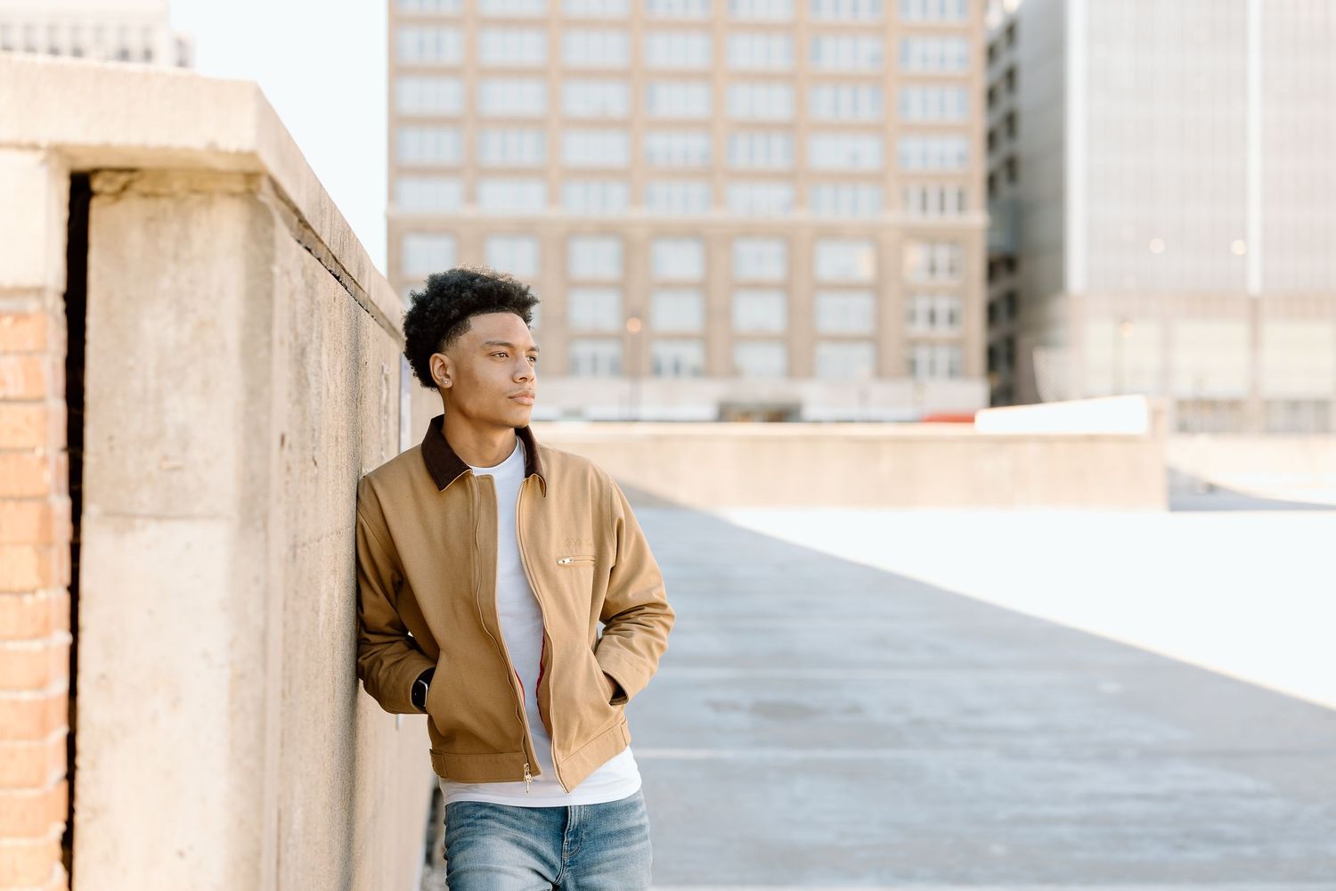 Casual street style portrait of someone leaning against concrete wall in urban setting.
