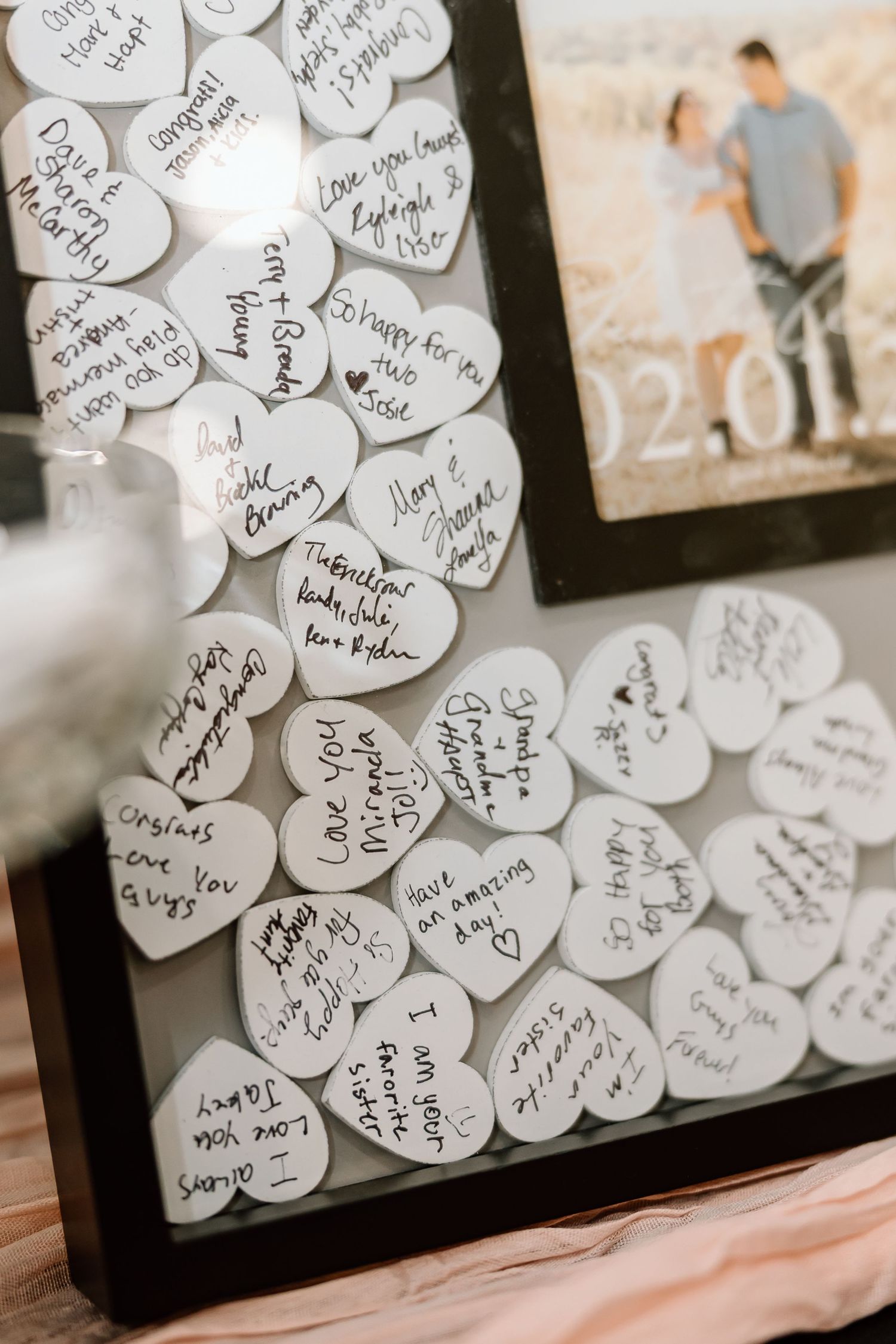 Close-up view of white paper hearts with handwritten messages arranged in a decorative frame display.