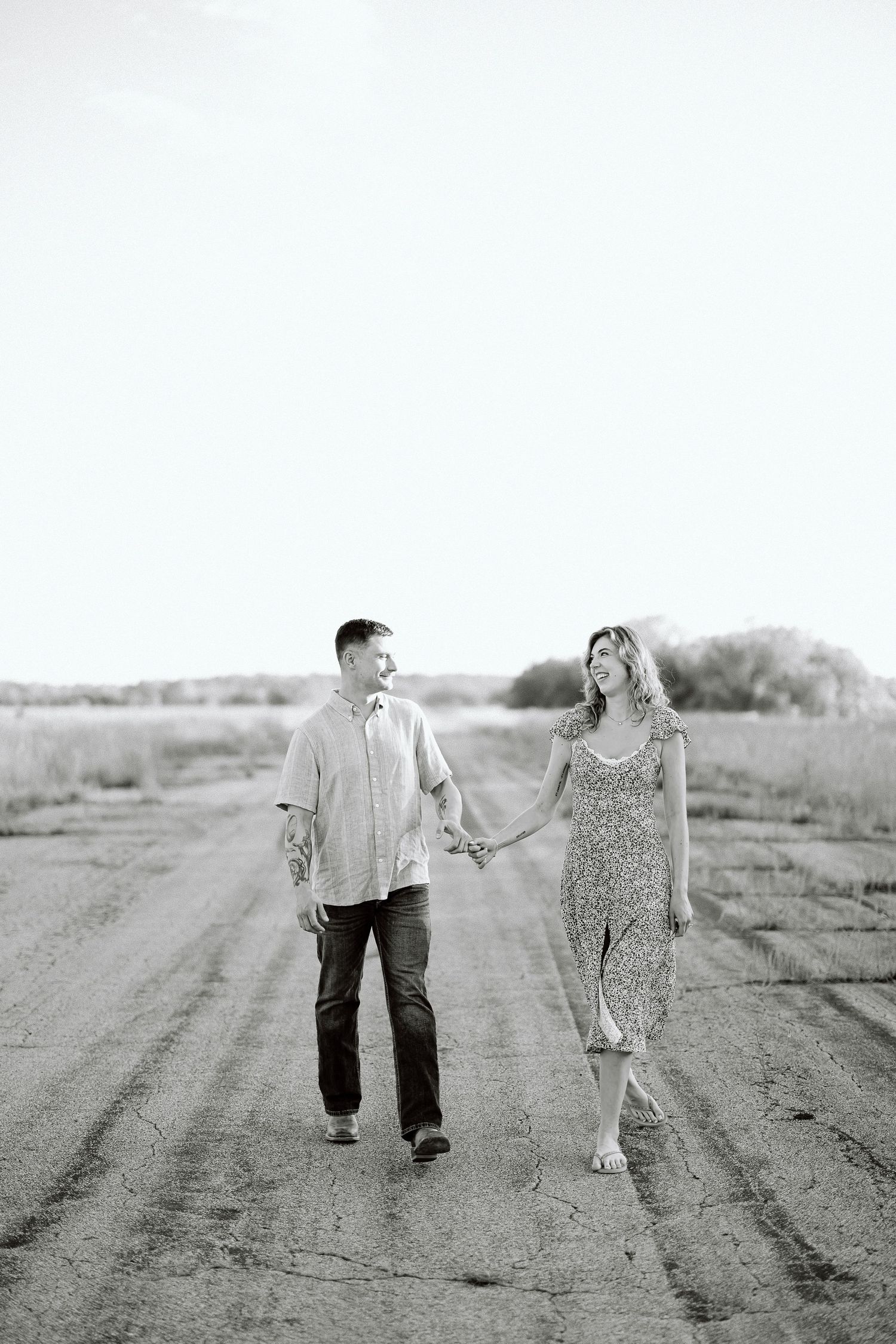 Black and white photo series showing a couple walking together on a dirt road in a romantic countryside setting.