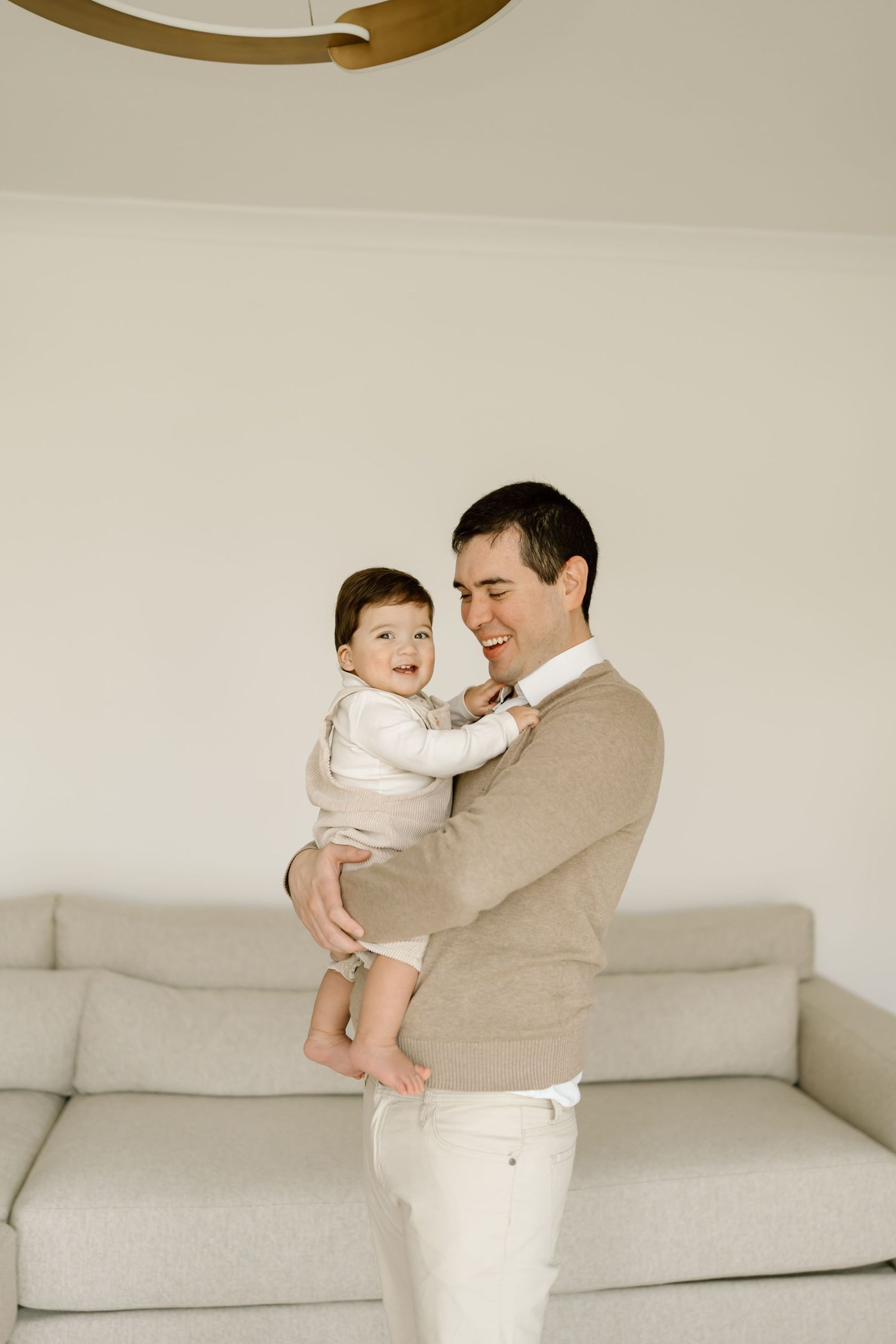 A series of four photos showing tender moments between a parent and baby on a white couch.