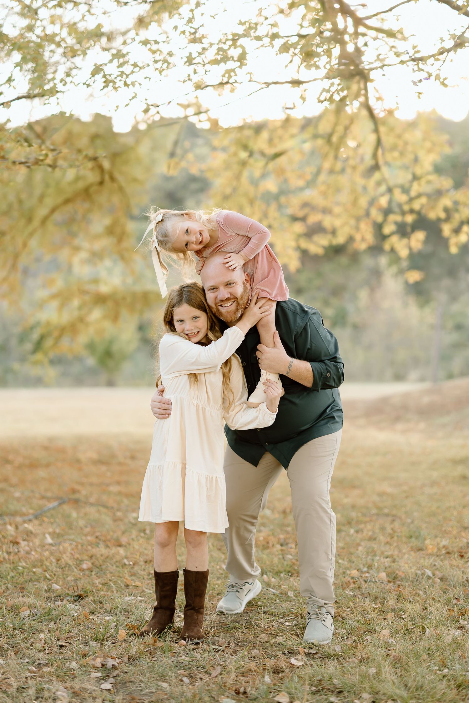 Two people share a tender moment together in a sunlit autumn field with golden foliage in the background.