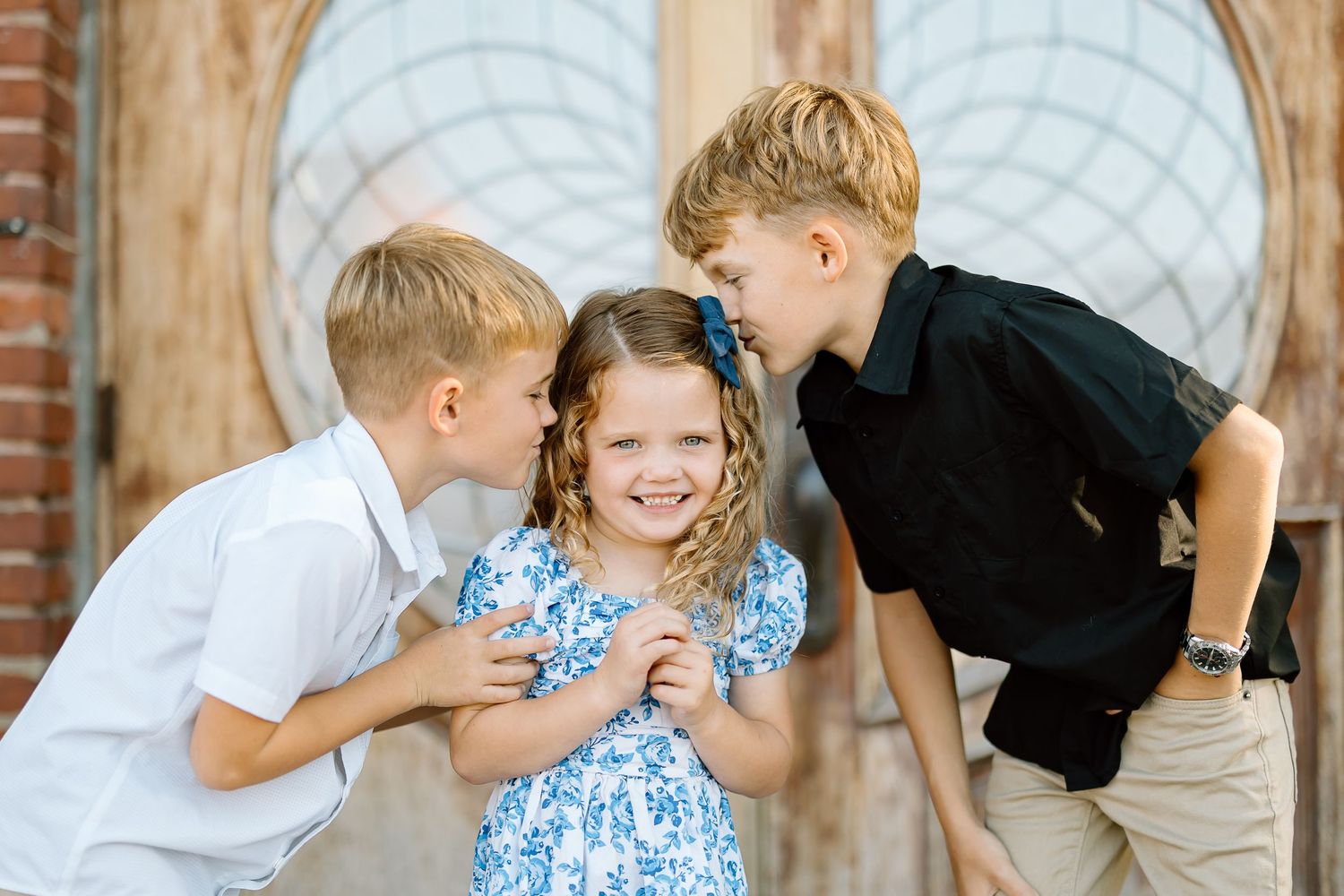 A series of candid moments showing children and adults interacting playfully in front of a brick wall with arched windows.