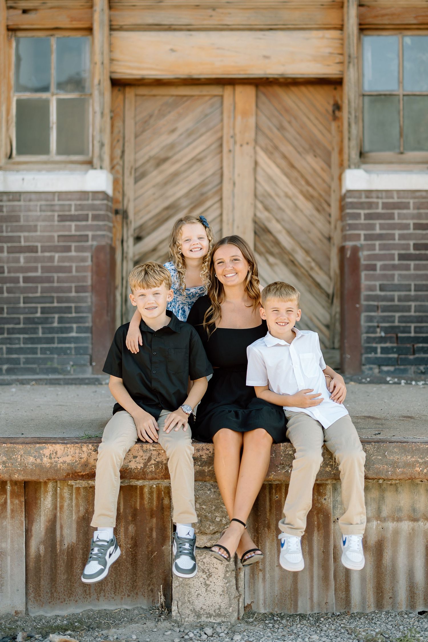Family sitting together on rustic wooden porch with brick and weathered wood background.