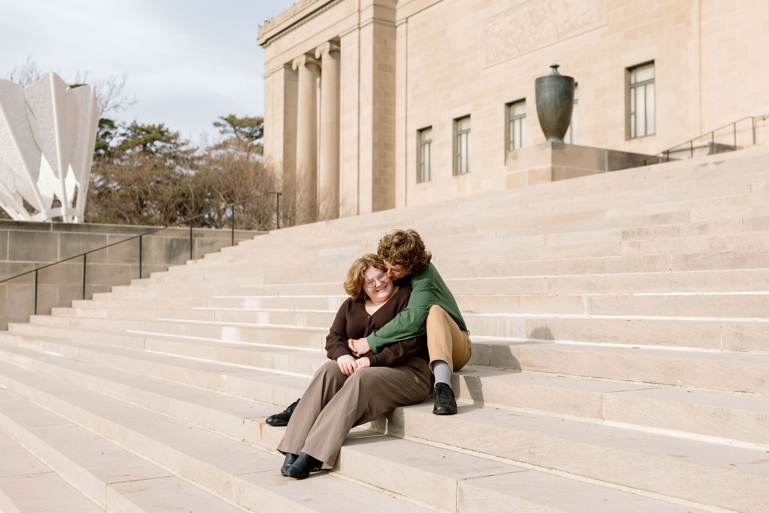 A series of concrete steps with people sitting and walking in front of a modern institutional building.