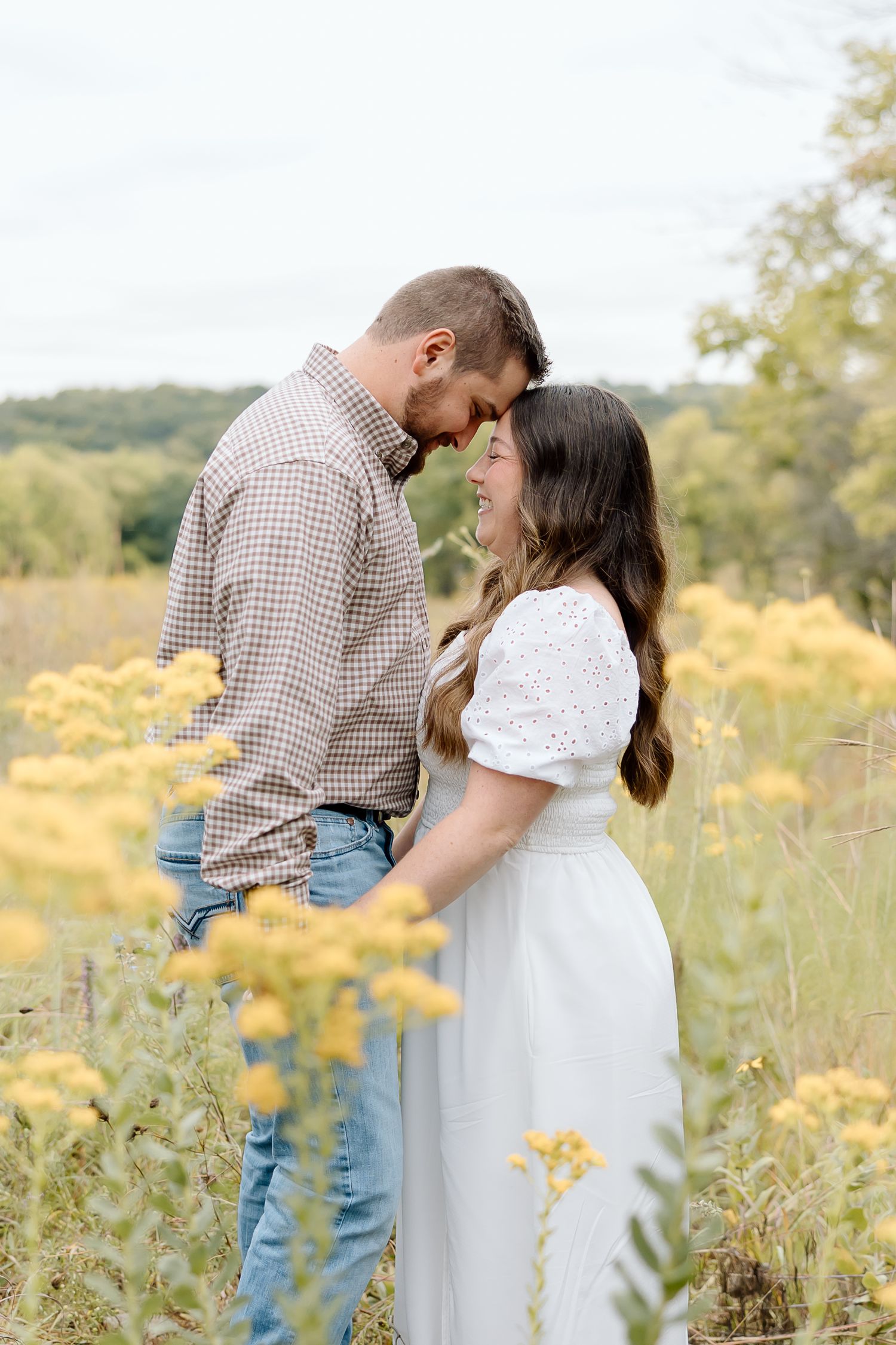 A tender moment between a couple standing in a field of golden wildflowers.