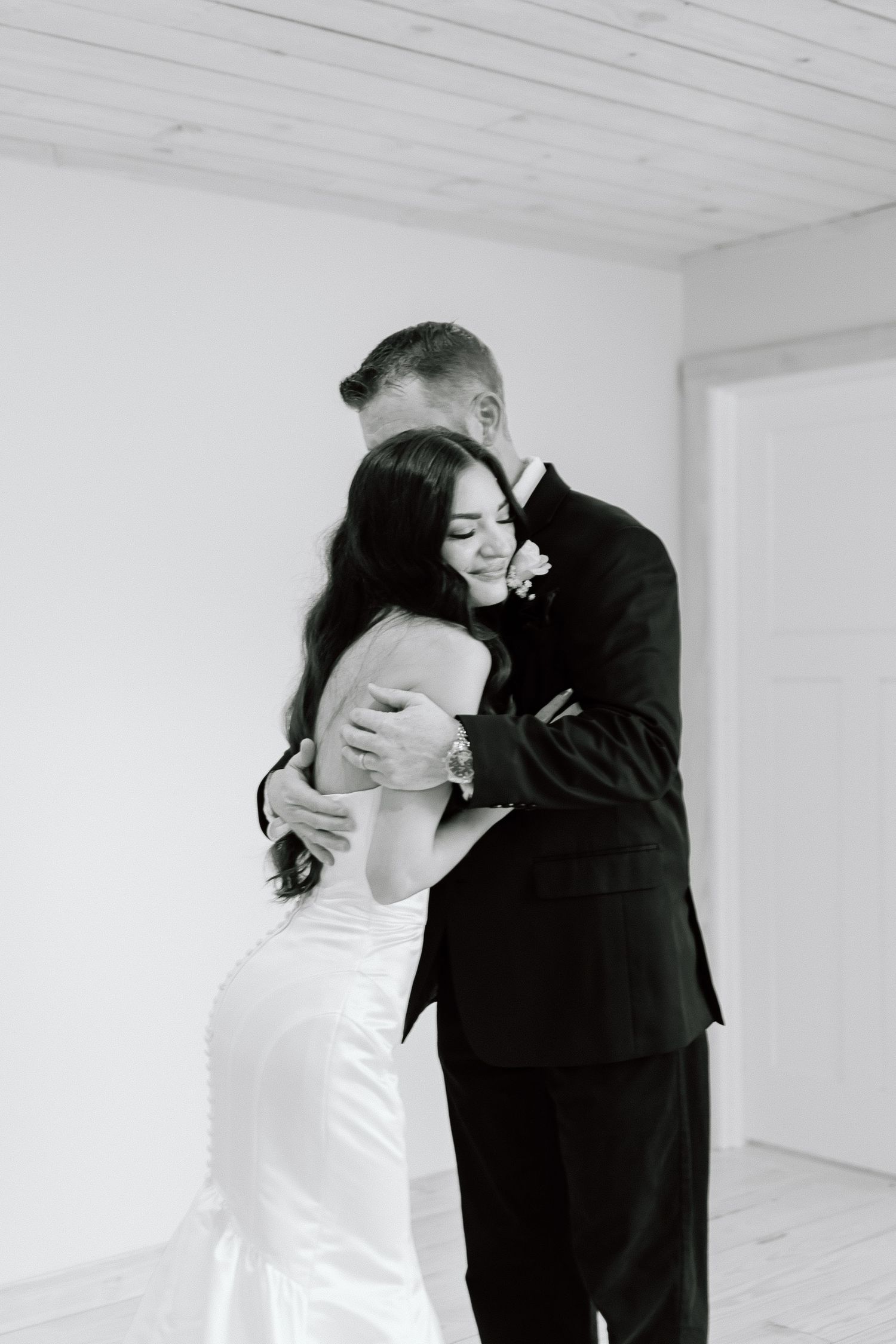 A romantic black and white photo series showing a couple in formal attire sharing intimate moments in a white room.