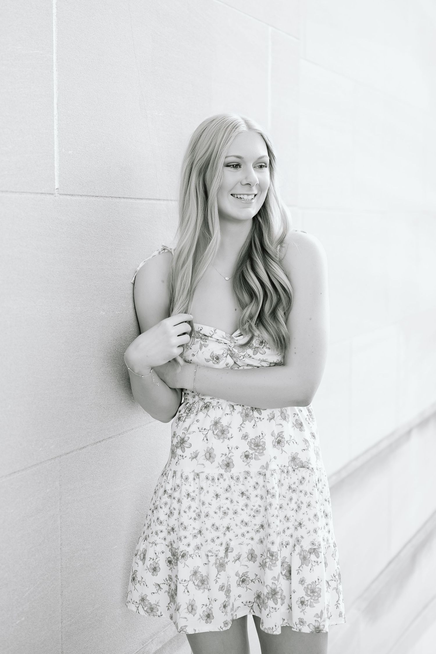 A series of four black and white portraits showing someone in a floral dress posing against a white wall.