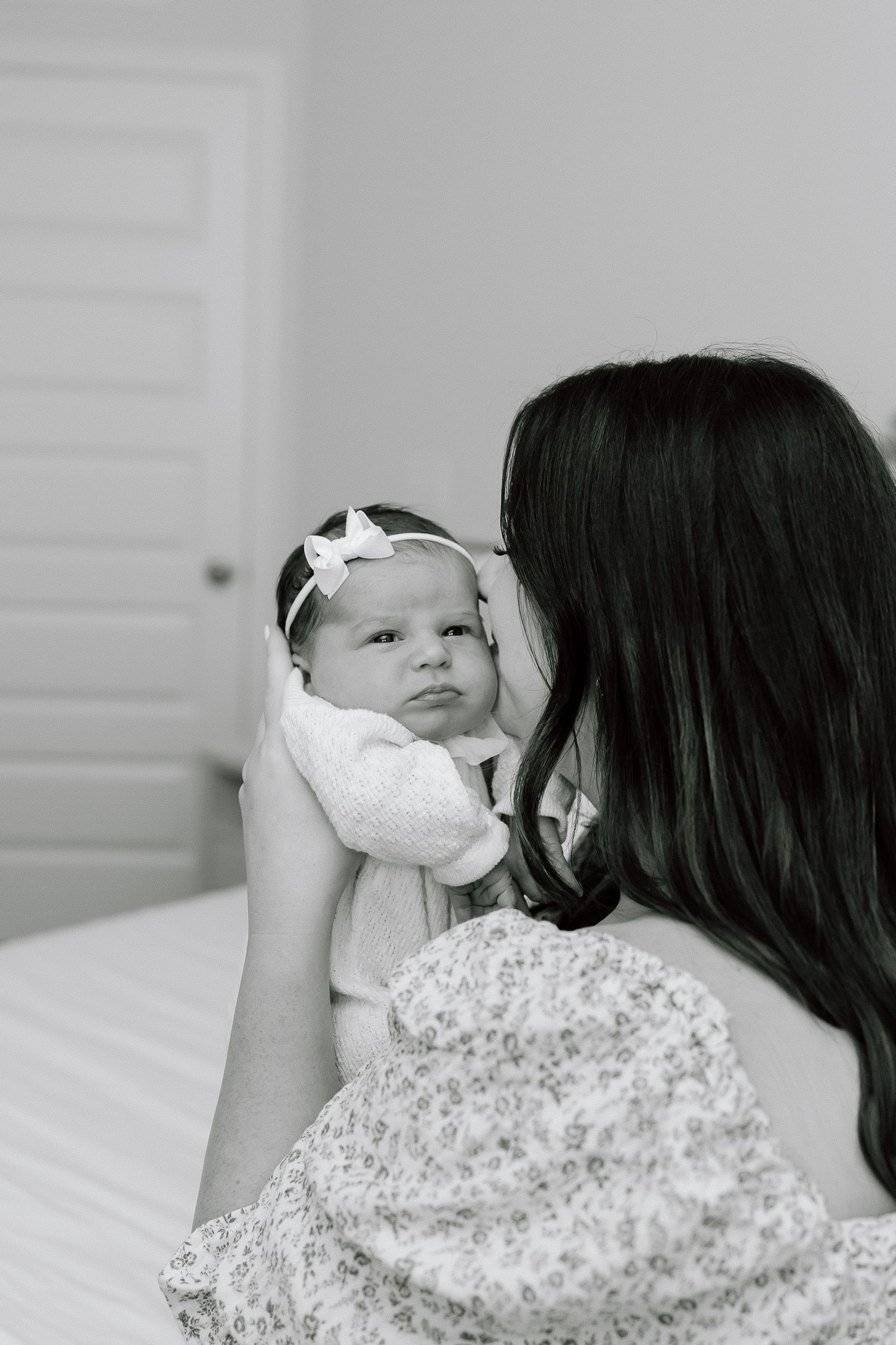 A tender moment captured in black and white as a parent holds and gazes at their newborn baby.