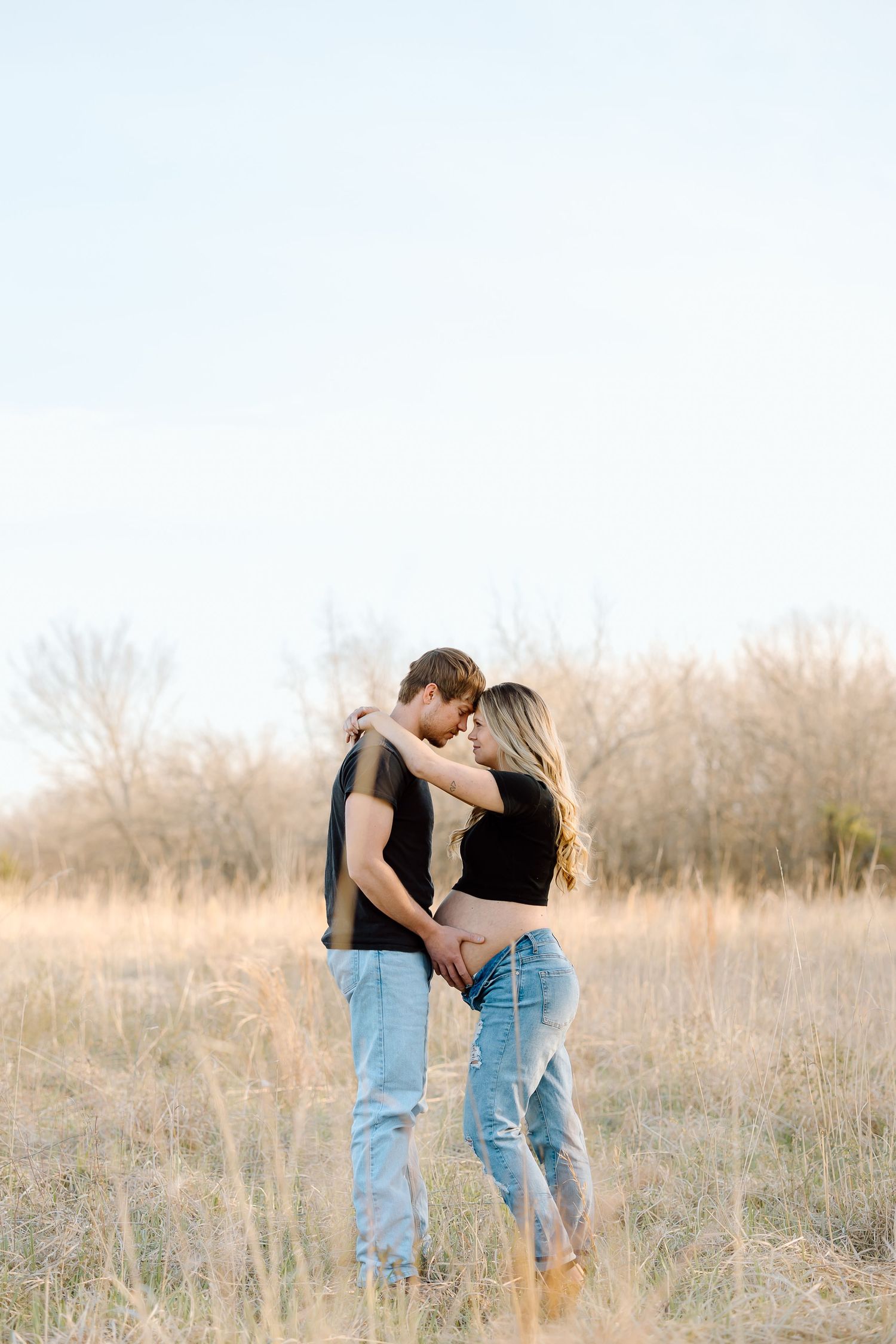 A romantic couple embraces in a golden field during sunset creating an intimate series of silhouettes.