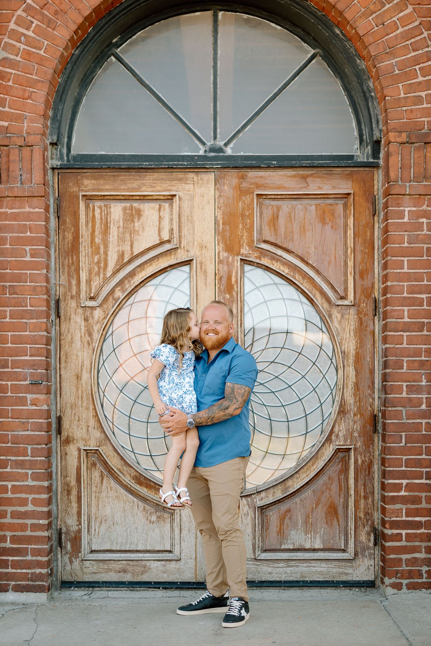 A series of four photos showing a couple in casual attire posing against a rustic brick wall with oval wooden doors.