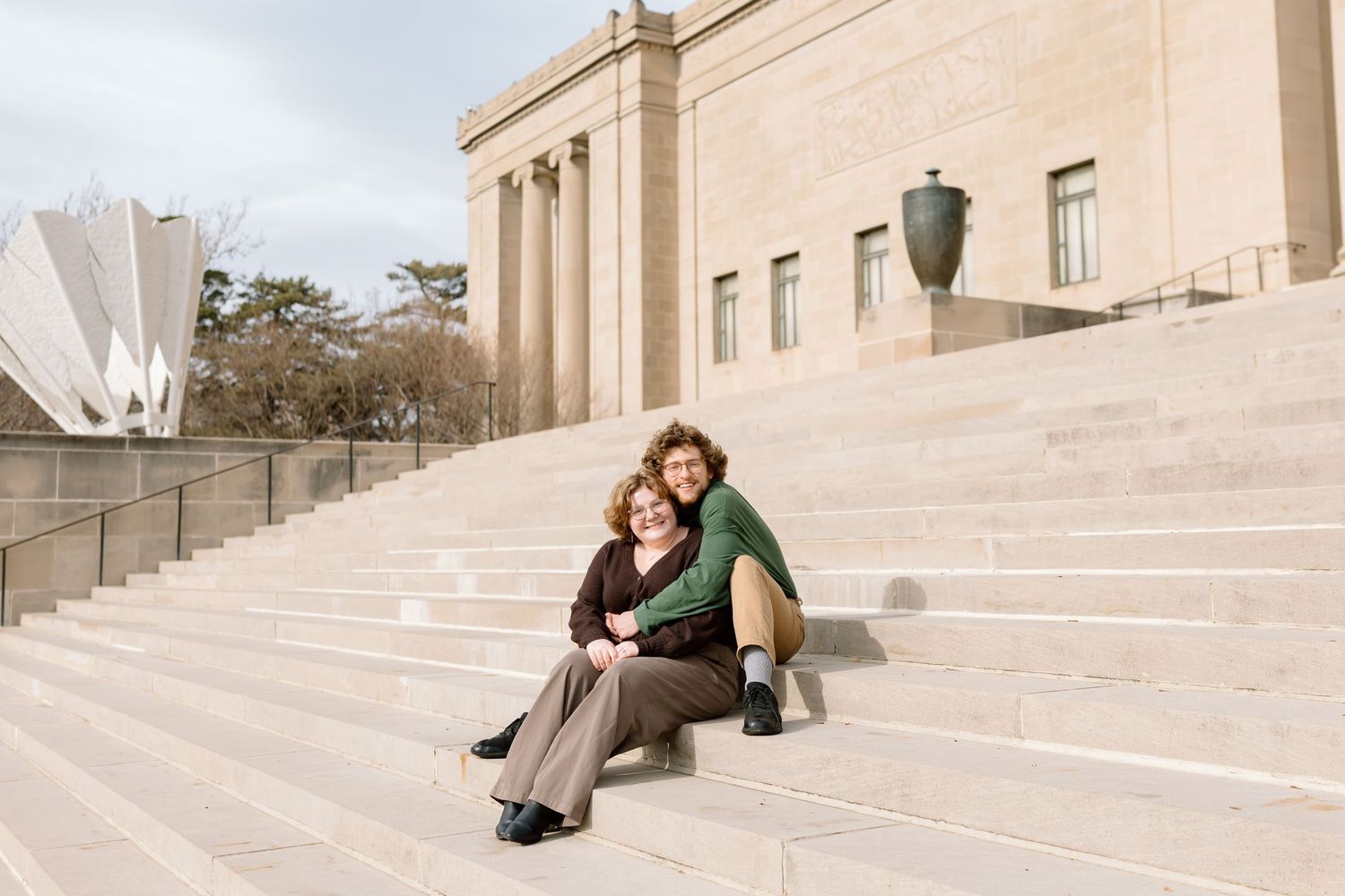 People sitting and lounging on the wide stone steps of a grand architectural building on a sunny day.