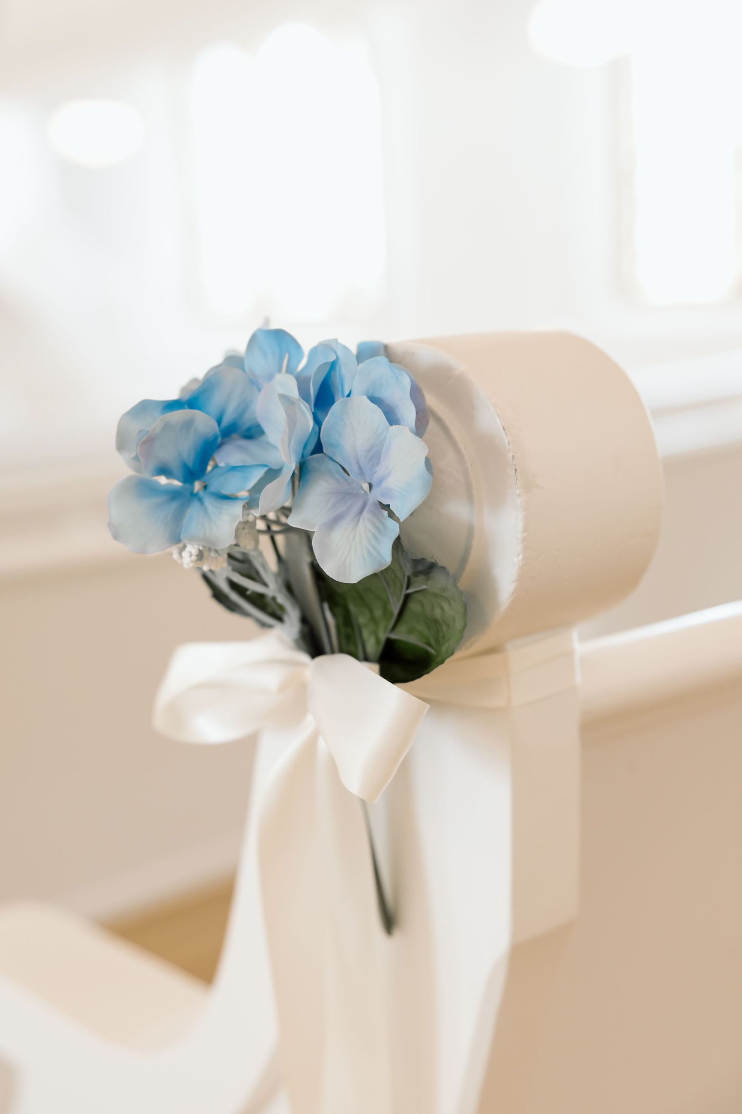 Blue hydrangea bouquet tied with white satin ribbon on a chair, perfect for wedding ceremony decor.