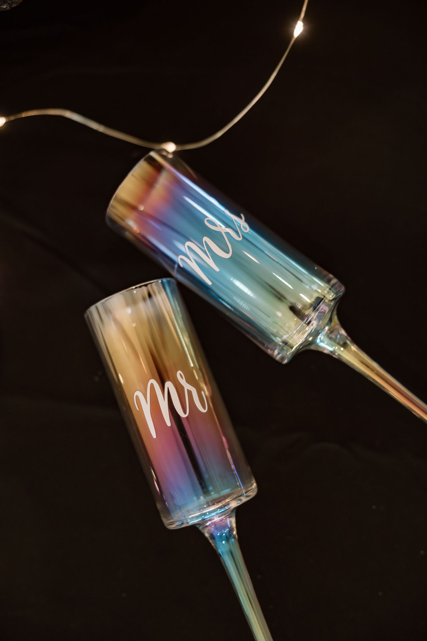 Iridescent glass pendant lights with holographic rainbow effects displayed against a dark background.