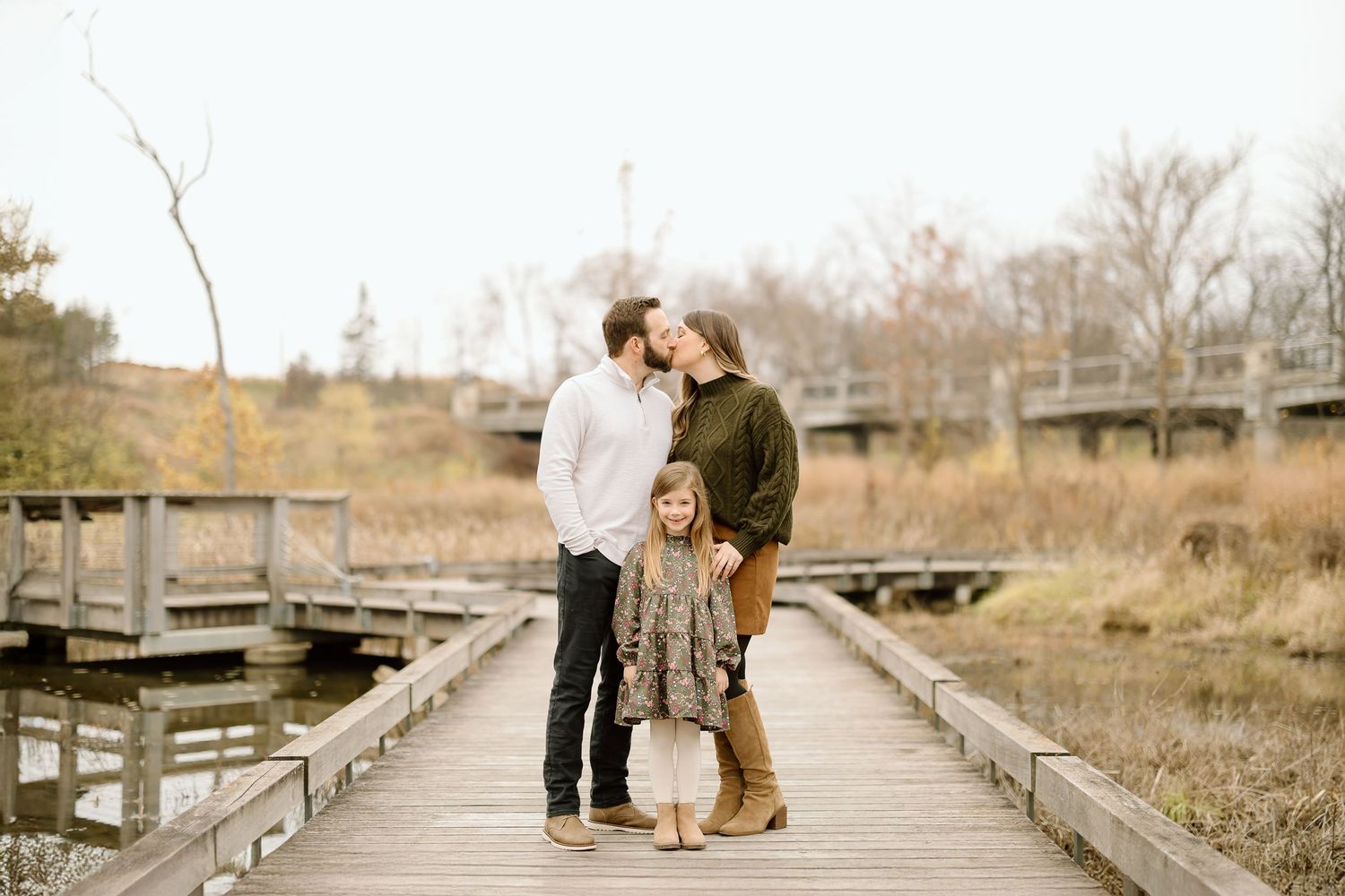 Candid family moment captured on wooden boardwalk during fall photo session.