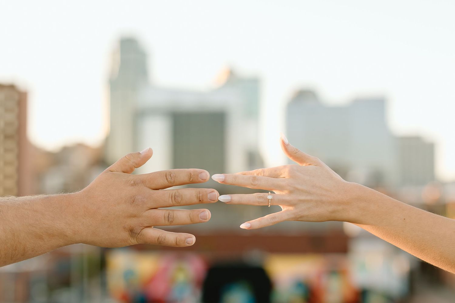 Two hands reaching out to touch each other against a blurred urban background.