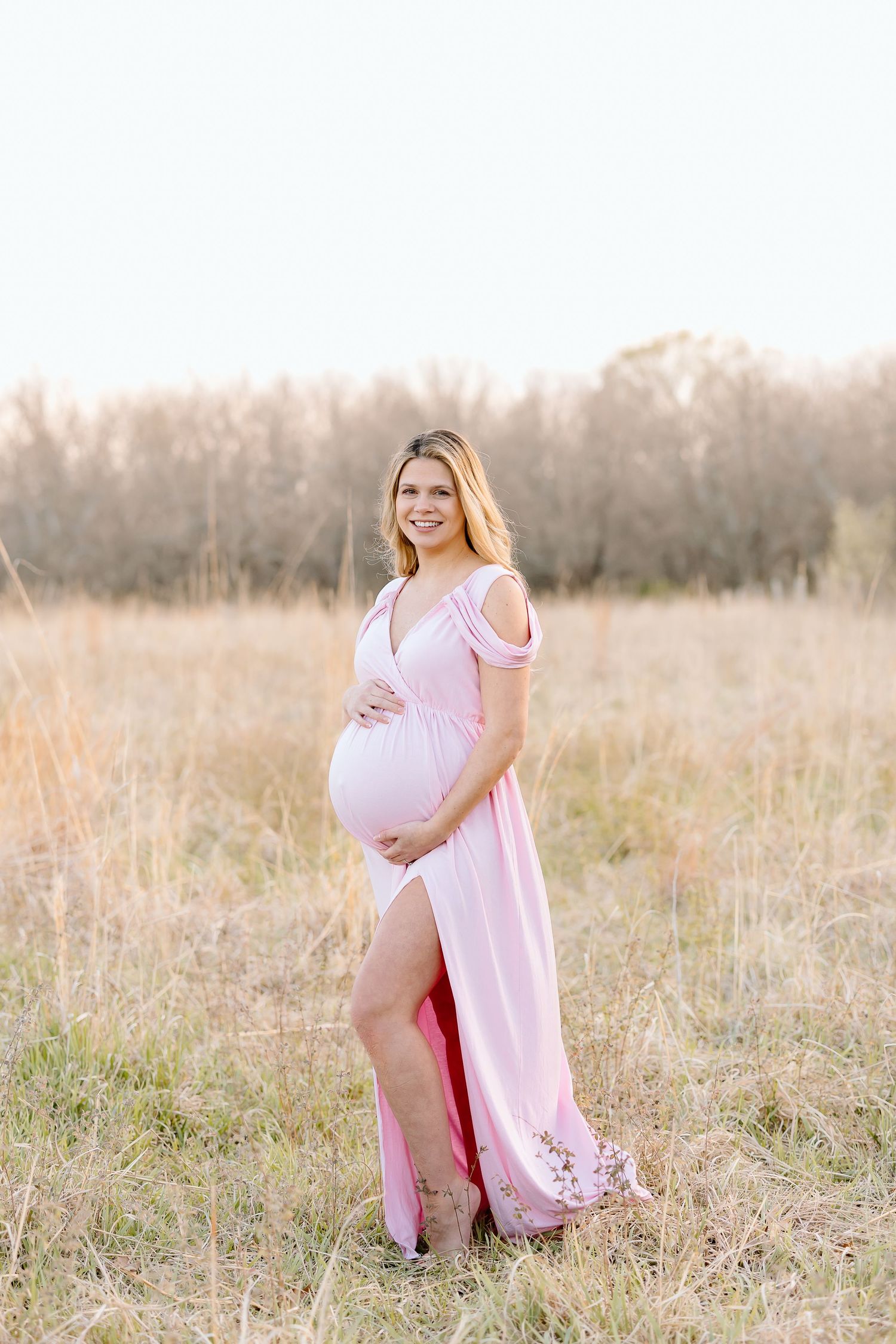 A series of maternity photos showing a person in a flowing pink dress posing gracefully in a sunlit meadow.