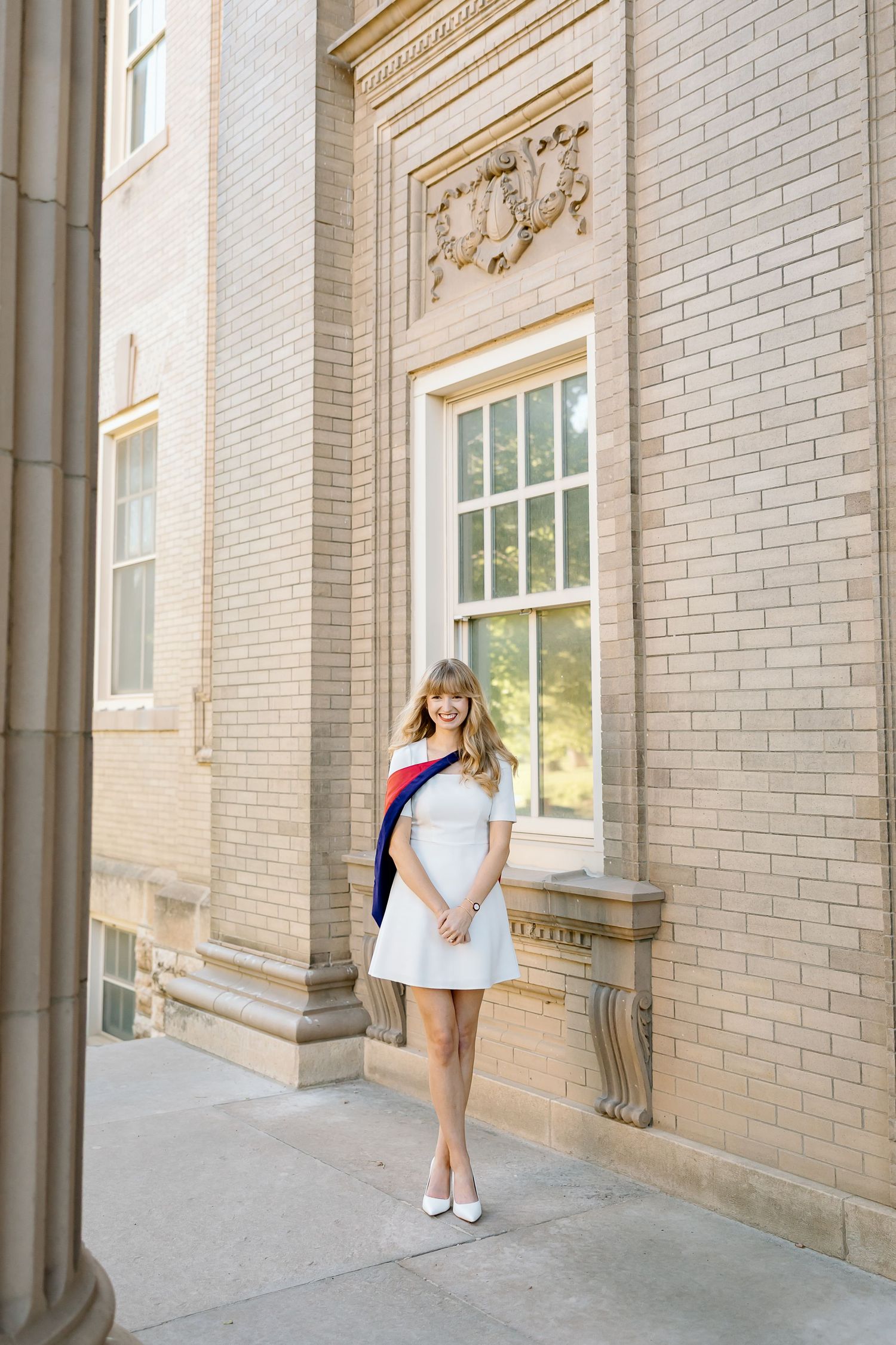 Three artistic poses against a beige brick building wall with ornate architectural details and white trim.