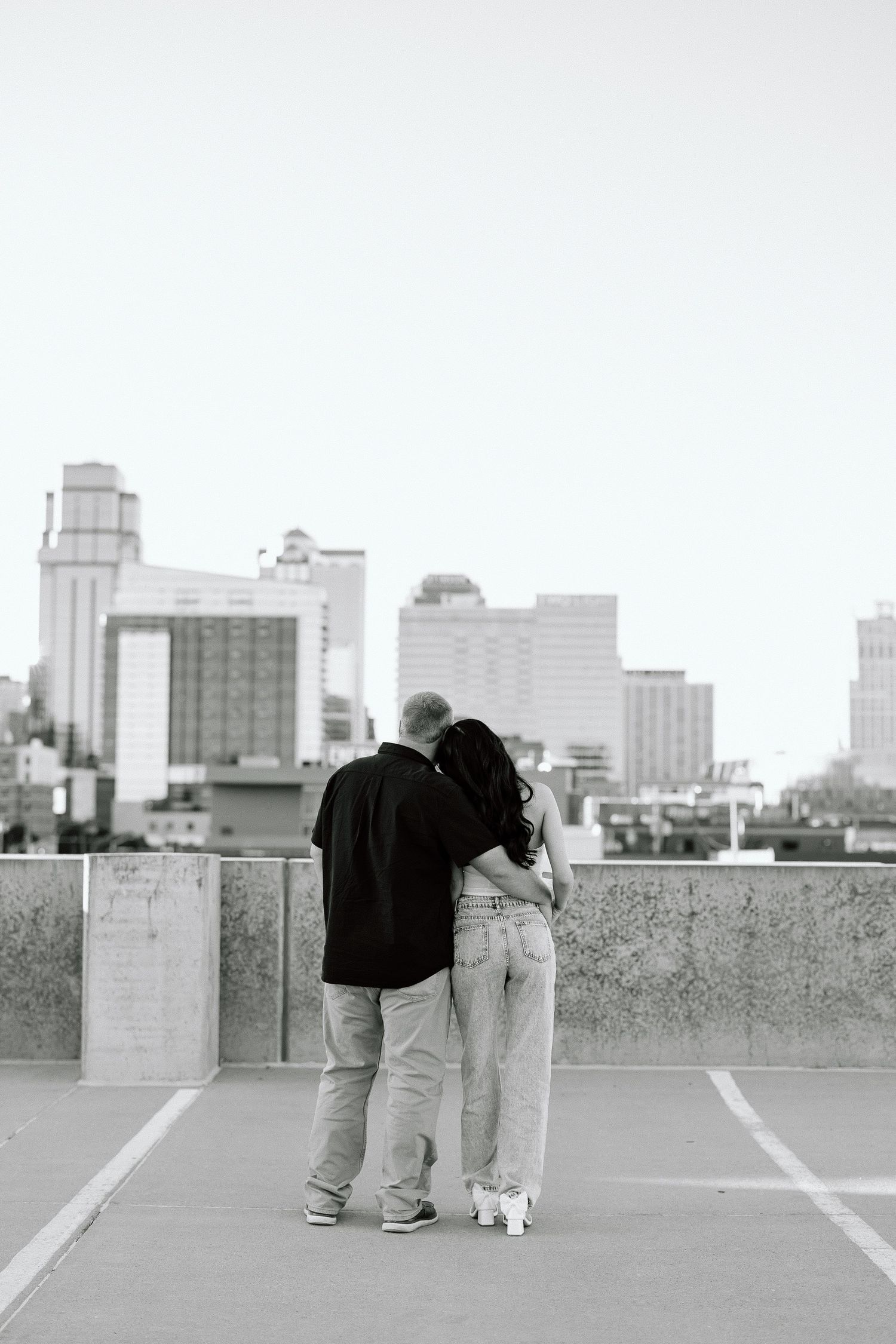 Three sequential black and white photos show people and a small white dog on an urban rooftop with city buildings in background.