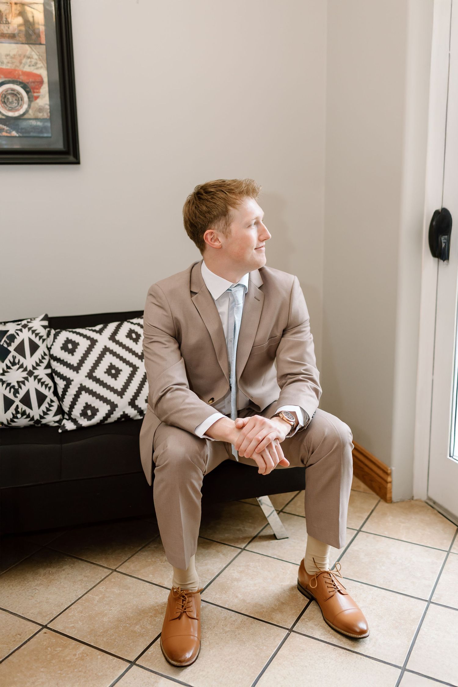 Three sequential photos show someone in a beige suit sitting on white tile flooring next to black and white decor.