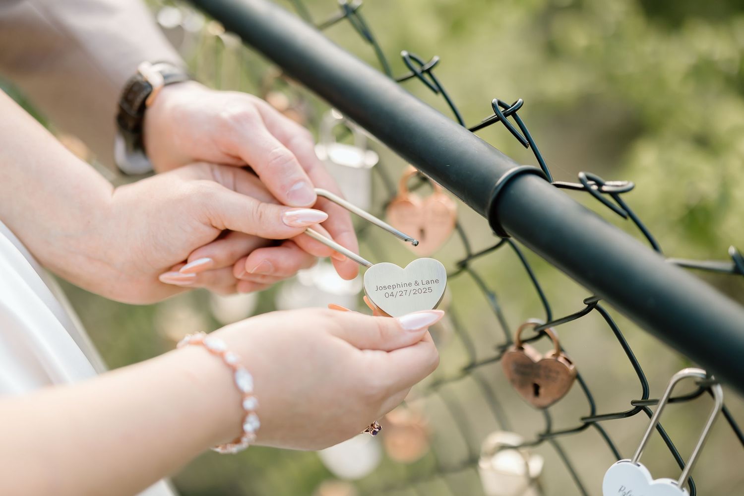 Hands holding a small compass against a wire fence in a soft outdoor setting.