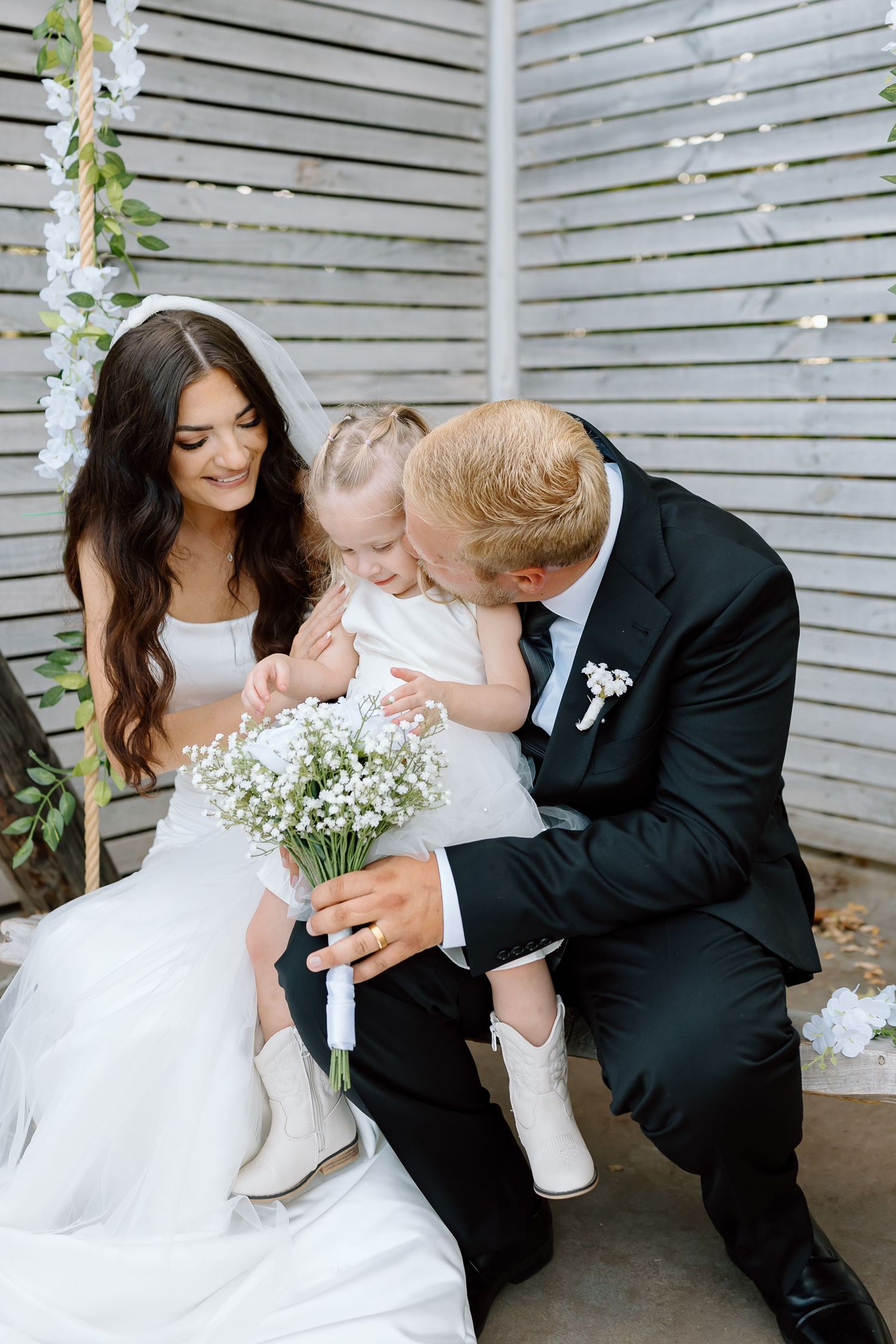 A sweet wedding moment captured in a series of photos showing a couple sharing kisses with a young child in formal attire.