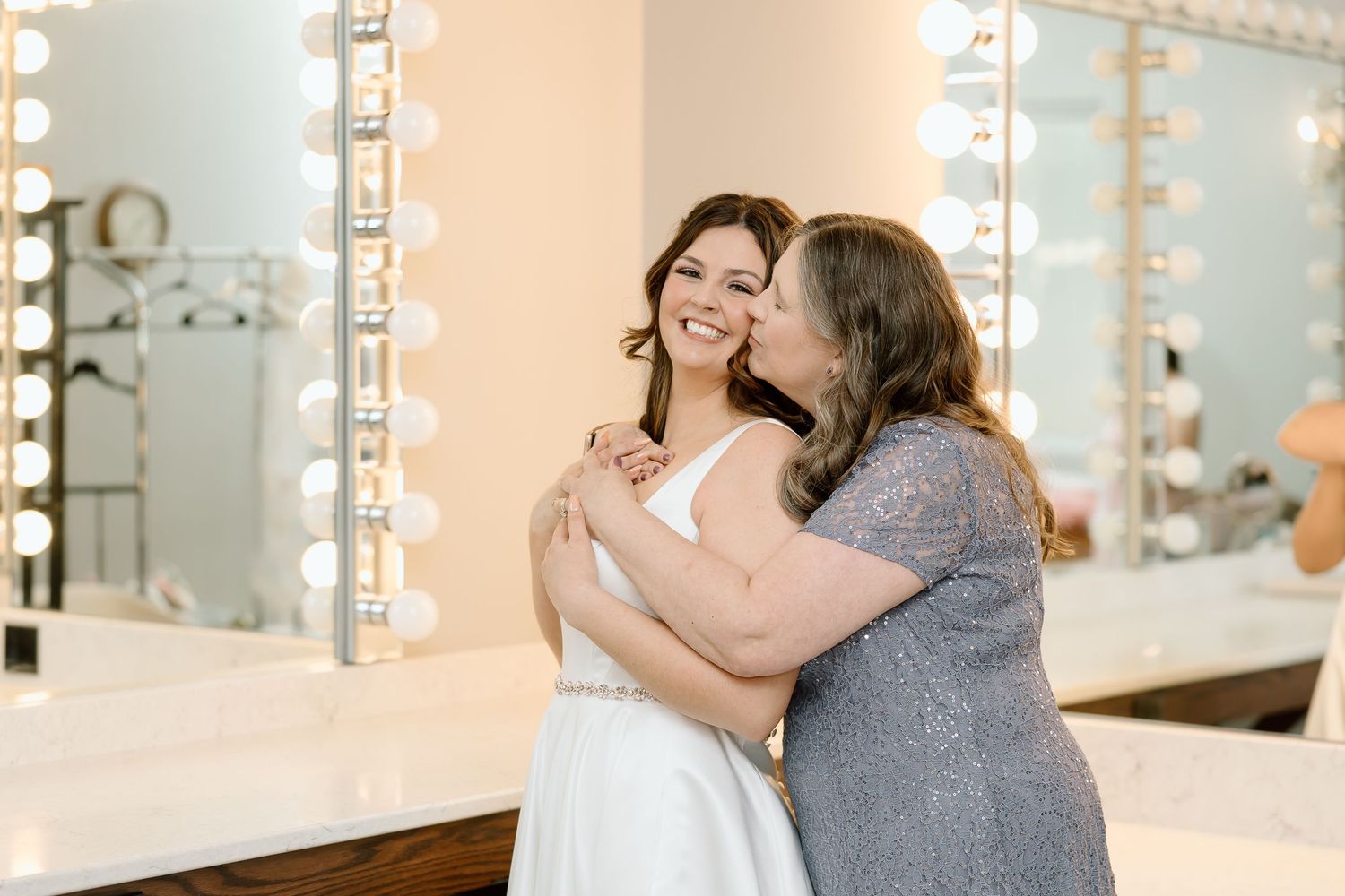 Two people embrace and dance together in a bright studio space with mirrored walls and warm lighting.