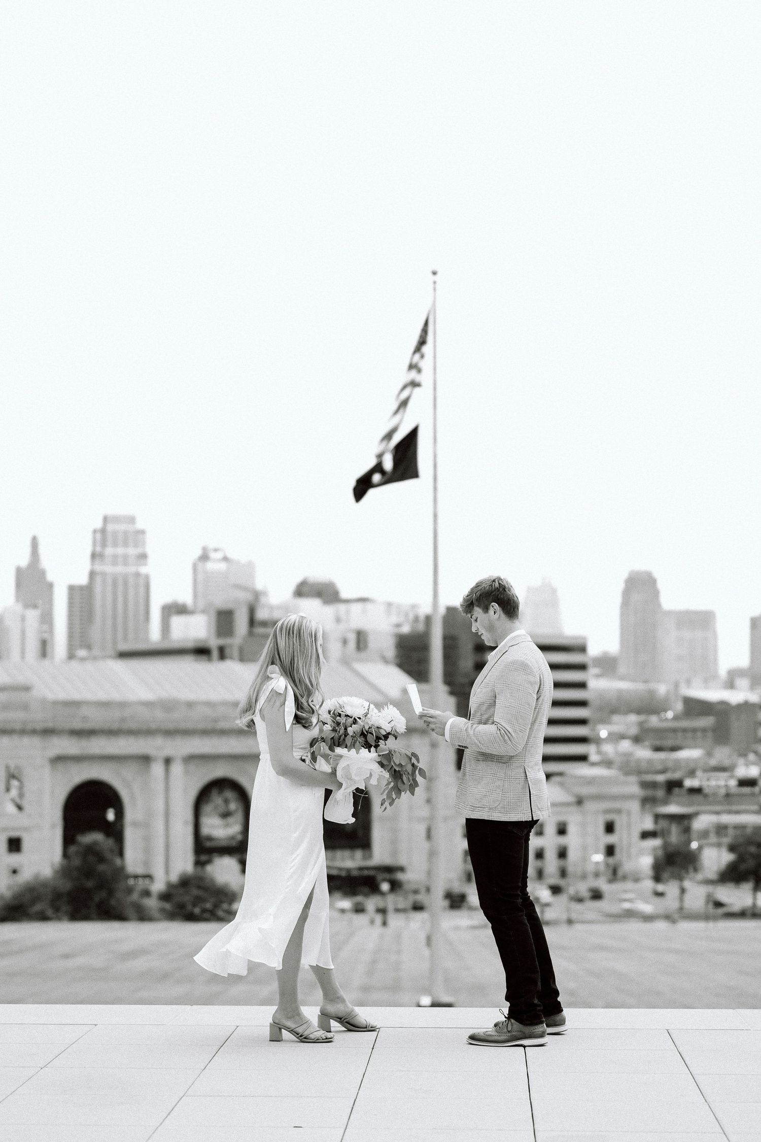 A sequence of black and white photos showing a marriage proposal on a rooftop with the city skyline in the background.