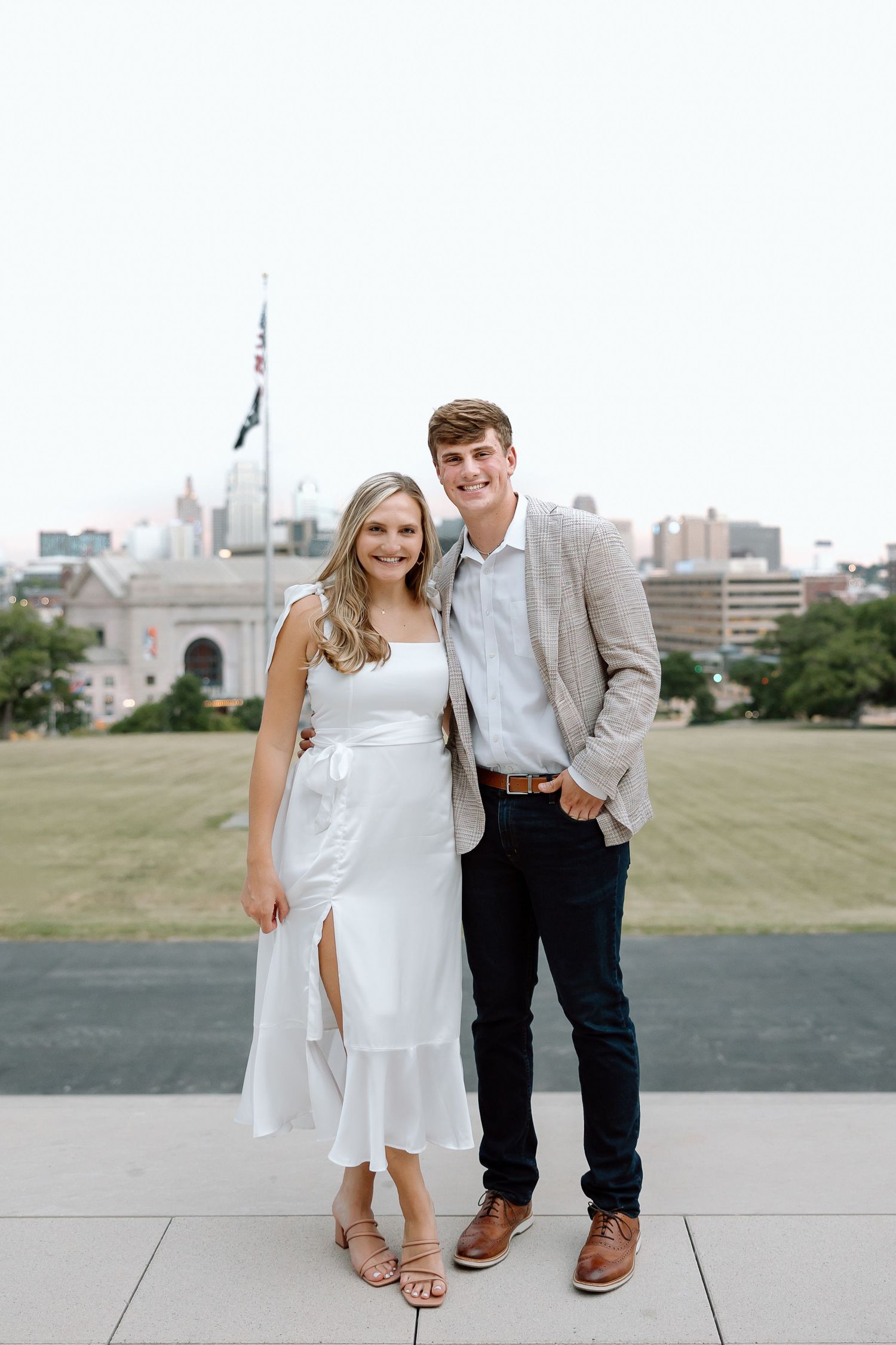 A couple poses together outdoors with the Toronto skyline and CN Tower visible in the background.
