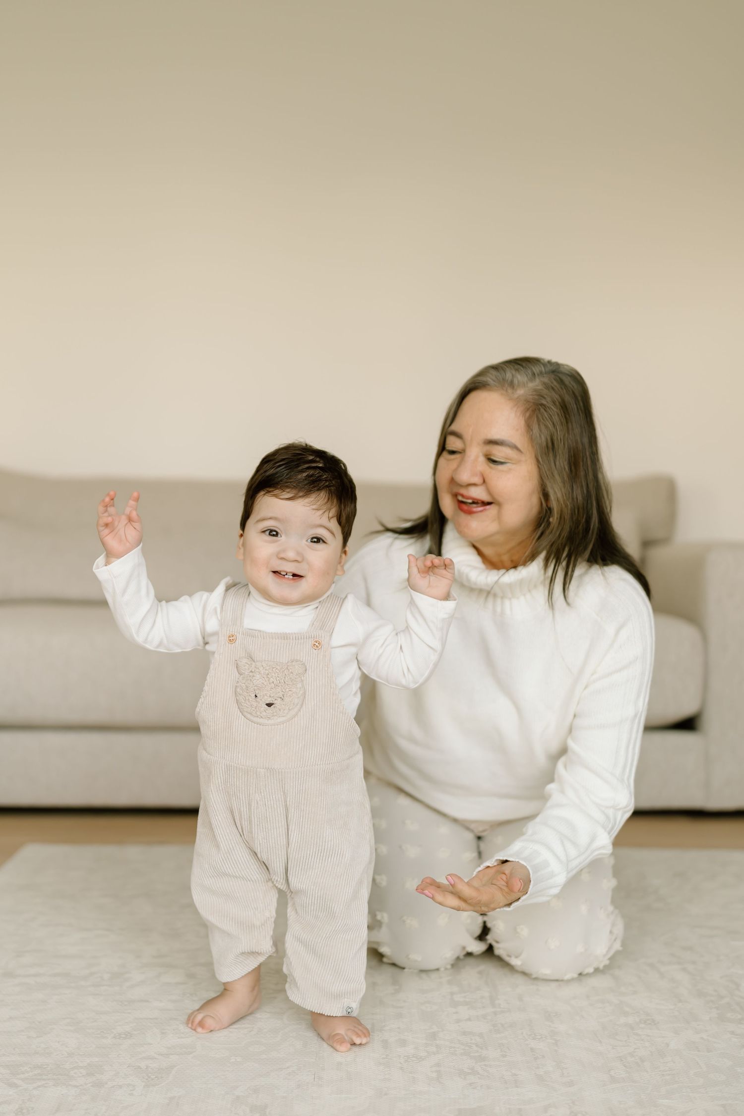 Two people wearing matching white outfits sit and play together on a light colored floor.