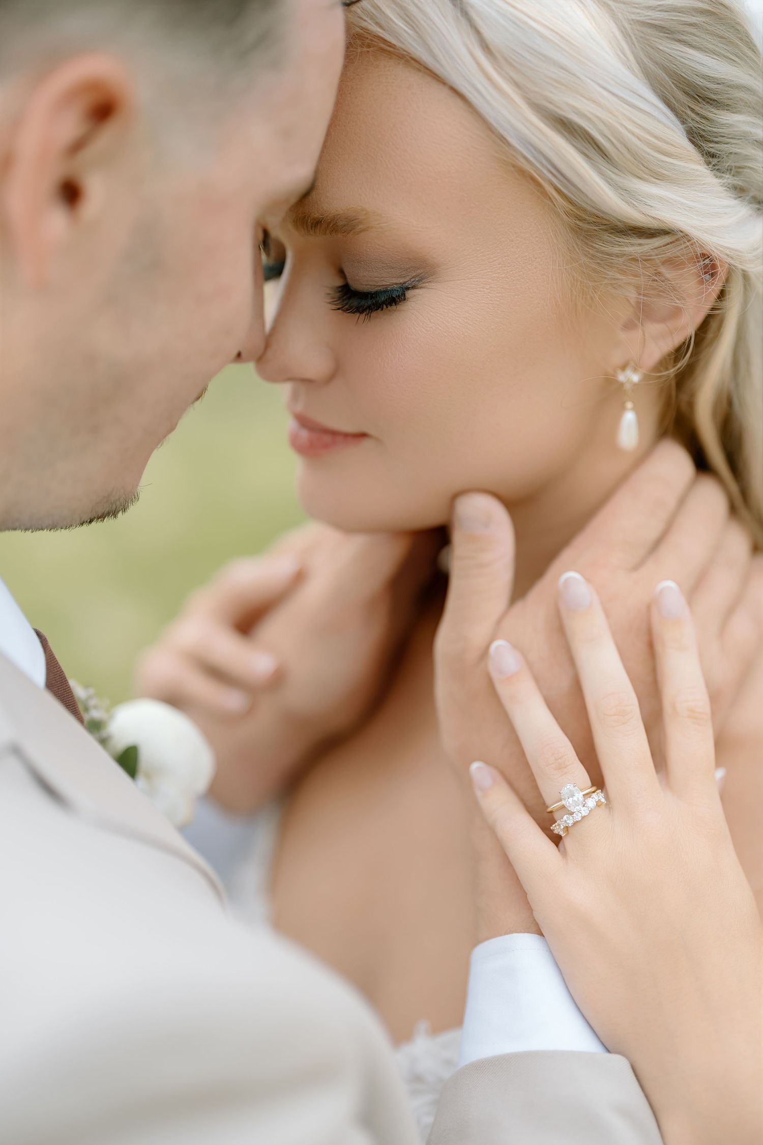 Bride and groom share an intimate moment, showcasing a diamond engagement ring and wedding band on her hand.