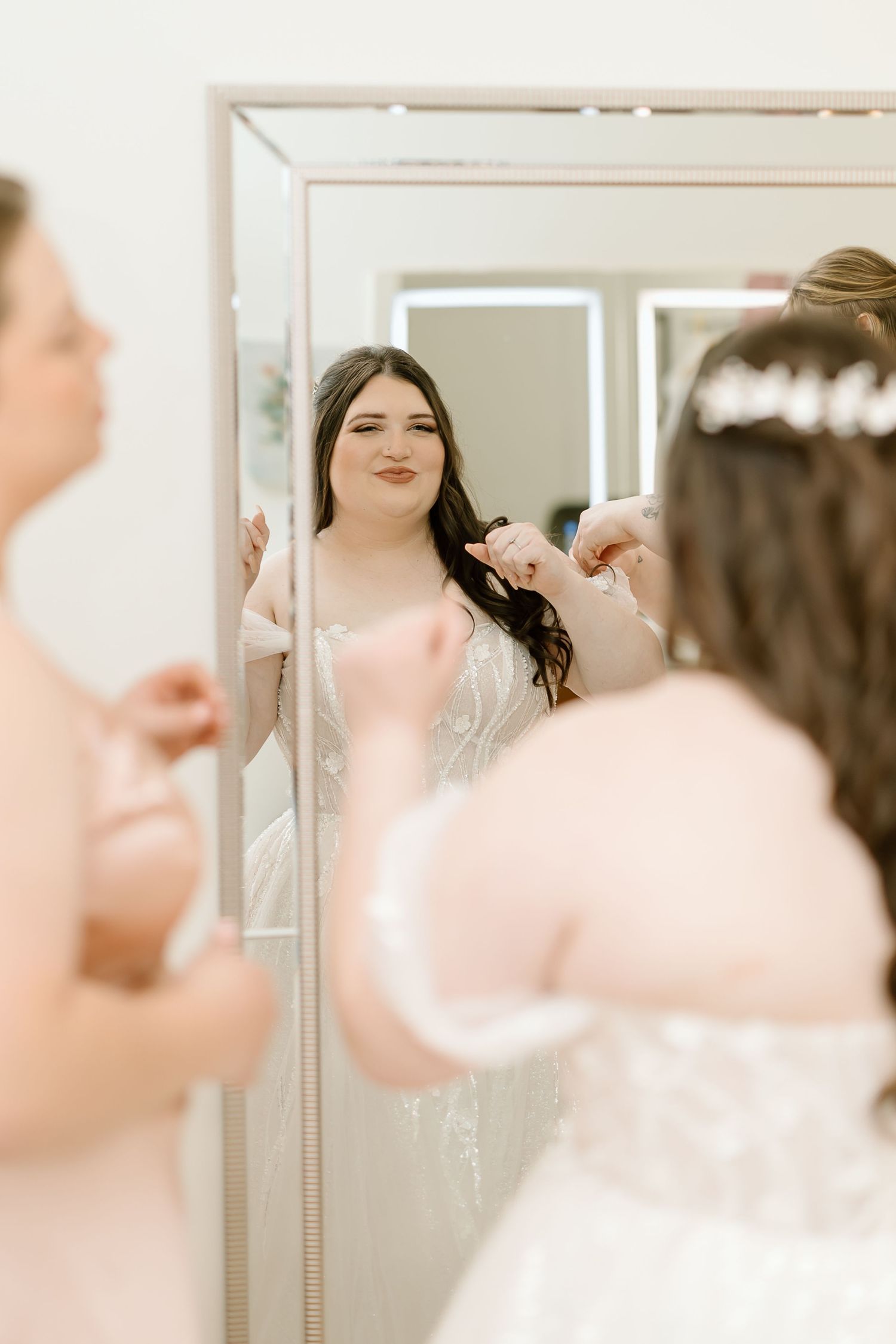 Bride getting final touches on hair and makeup in bridal suite mirror.