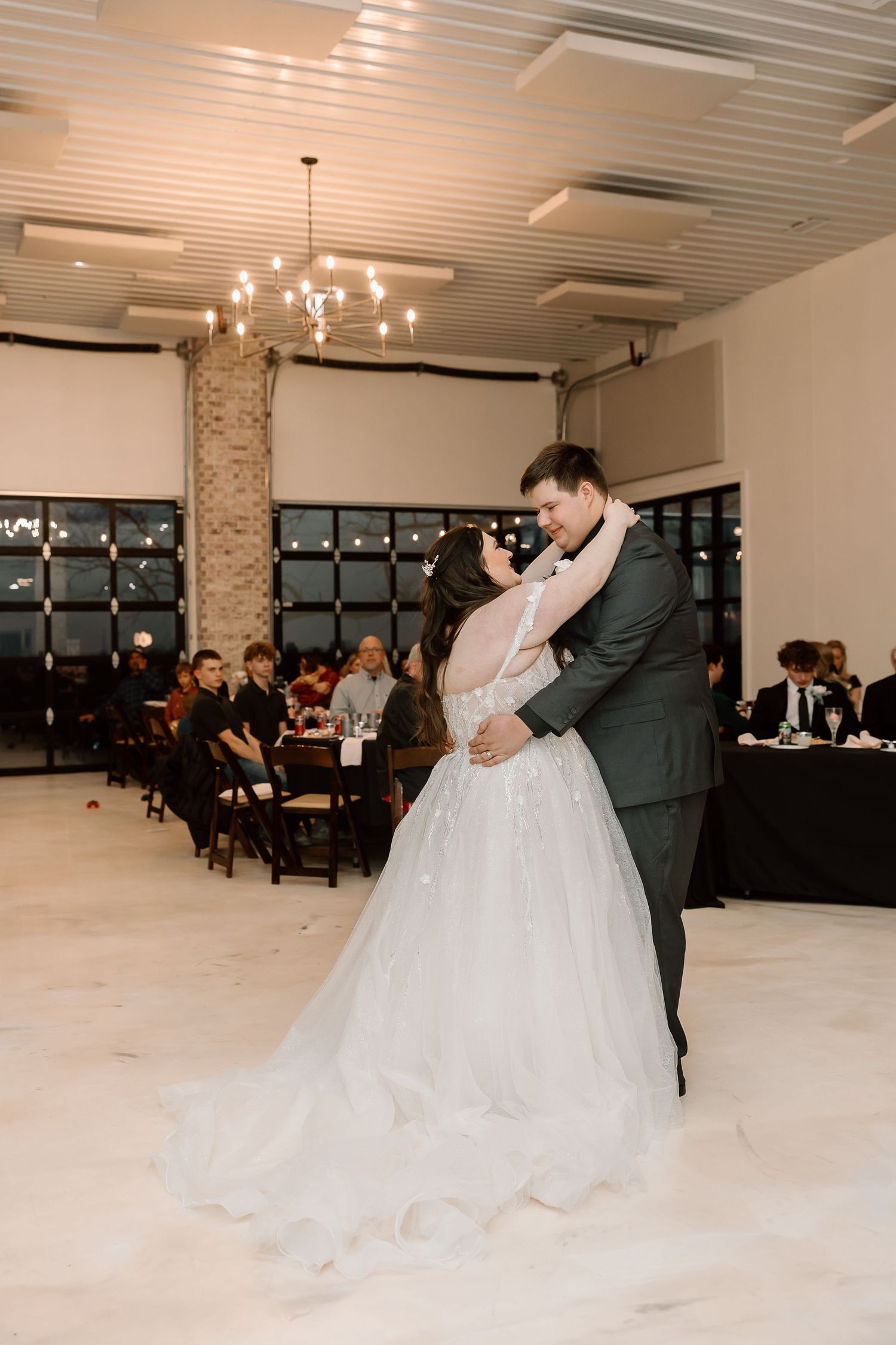 First dance in elegant reception venue with modern lighting and guests watching.
