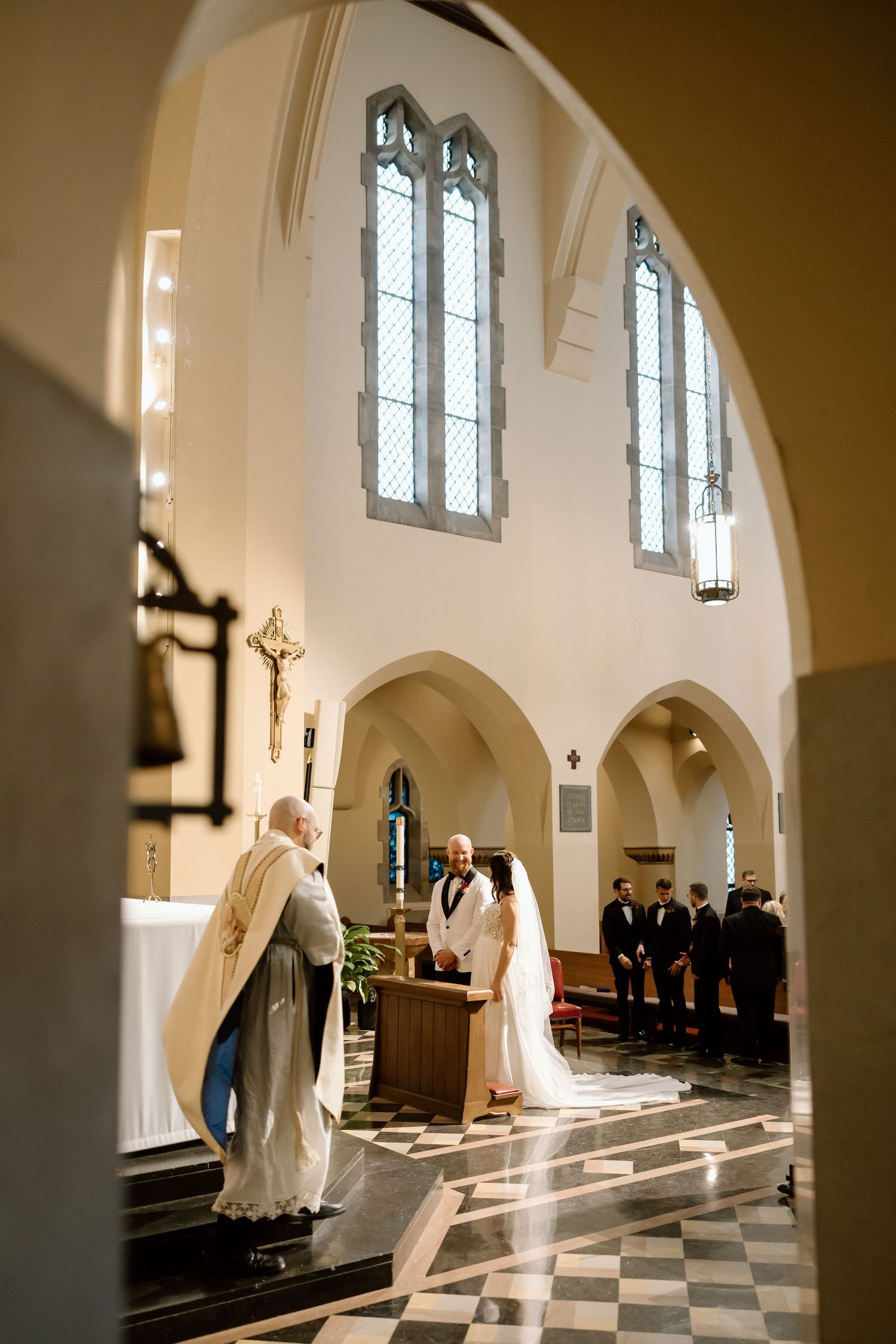A series of four photos showing figures in white robes moving through a sunlit church interior with checkered floors.