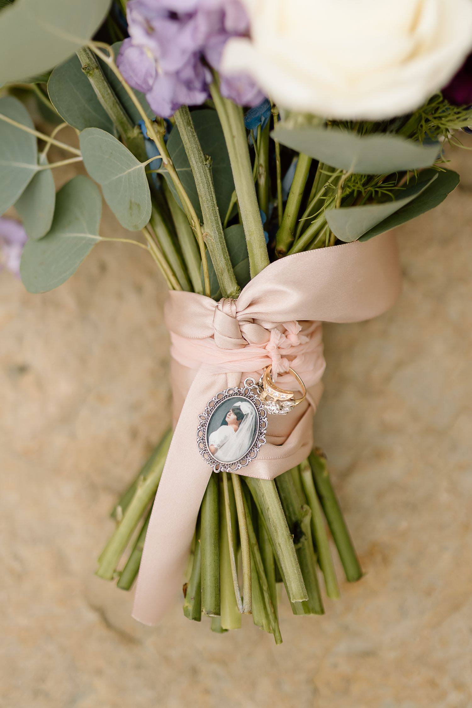 Wedding bouquet wrapped in blush ribbon with vintage locket charm attachment.