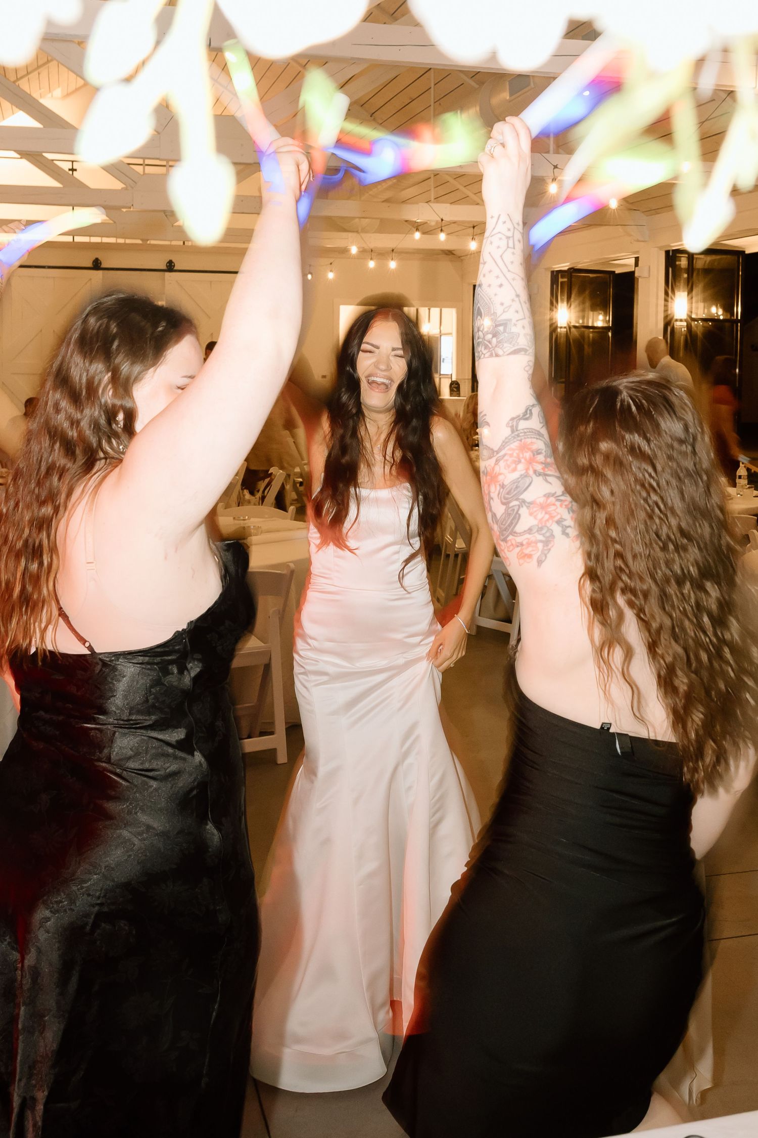 People dancing and celebrating at a party with colorful lights in the background.