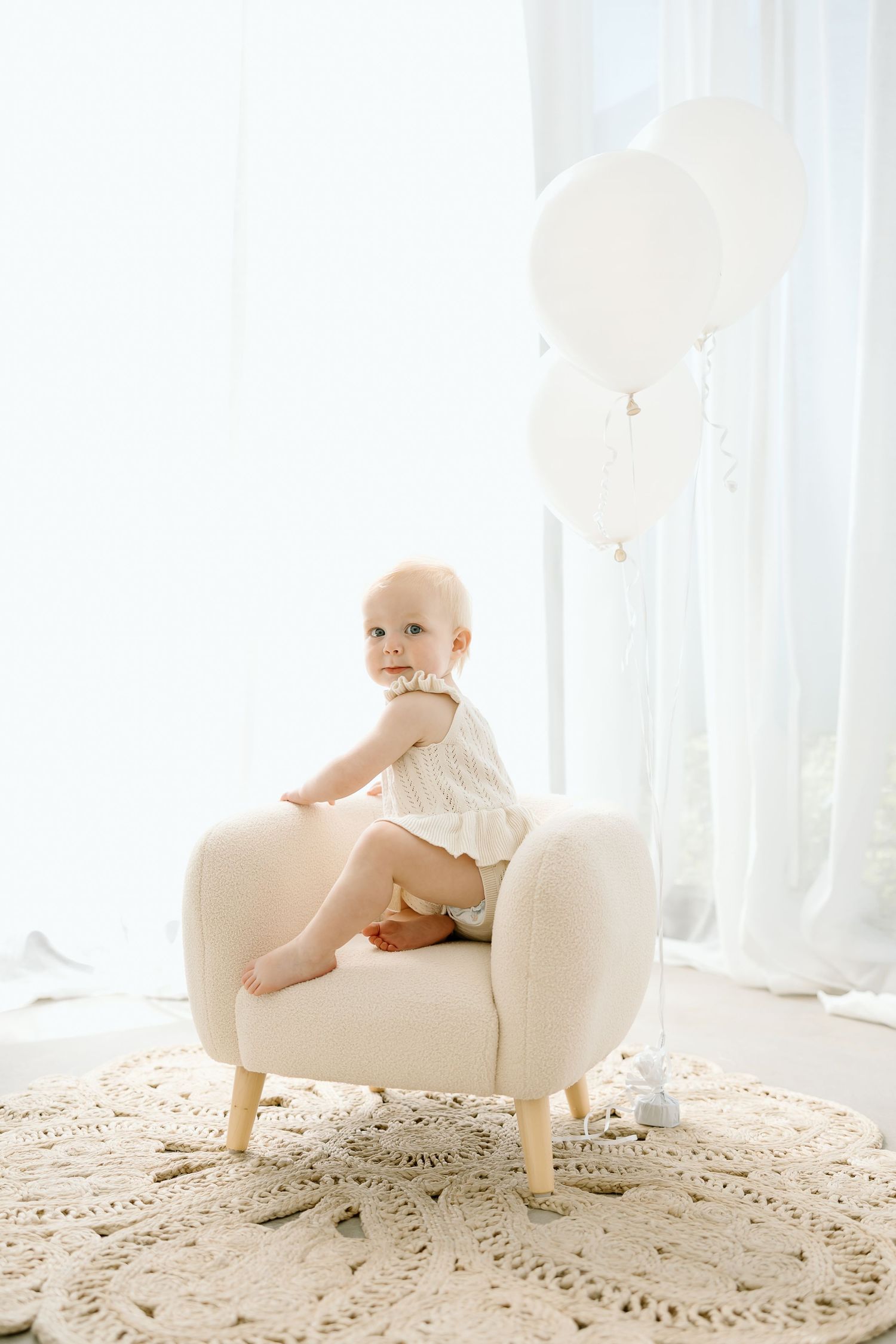 A series of artistic baby photos with white furniture and lace against a bright window background.