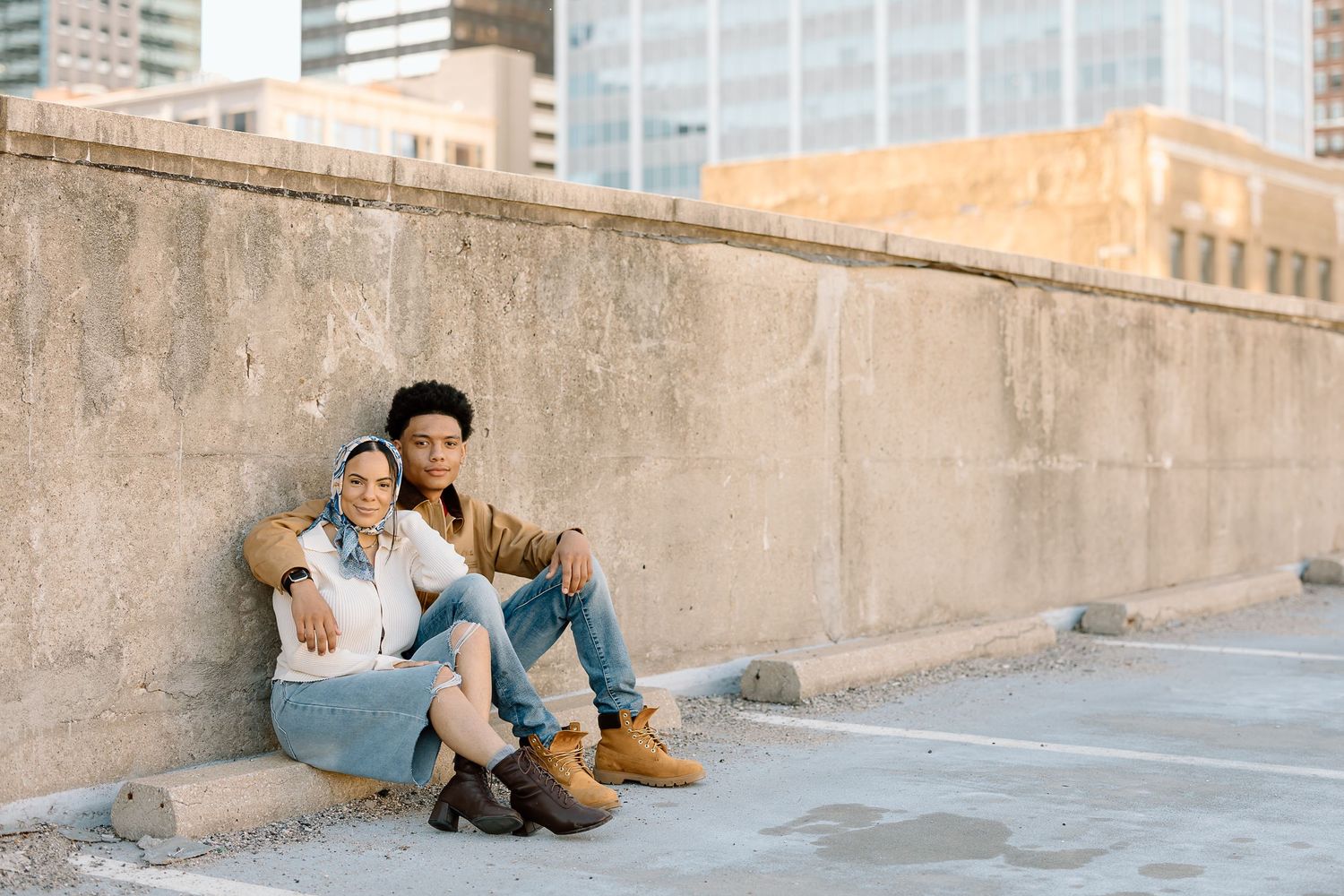 Casual lifestyle portrait on rooftop with urban skyline and concrete wall.