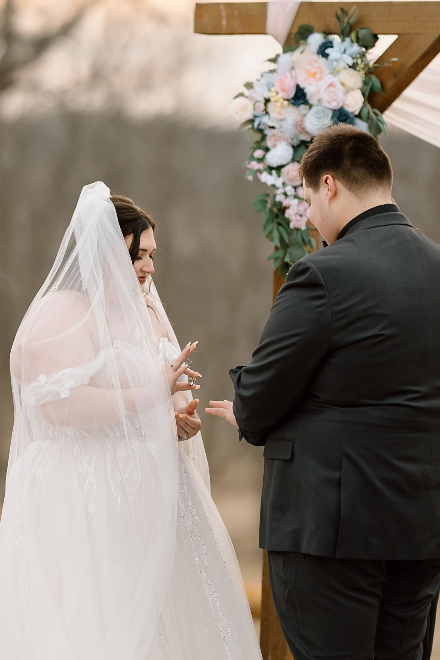 Emotional first look moment between bride in white dress and groom in black suit during wedding ceremony.