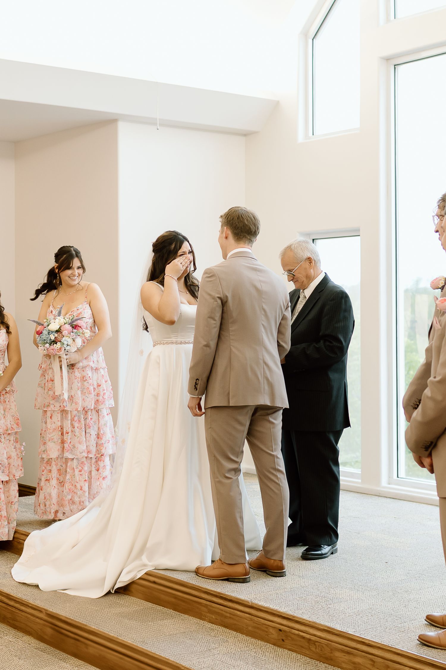 Four sequential photos show a tender first look moment between a bride in white and others in a bright sunlit room.