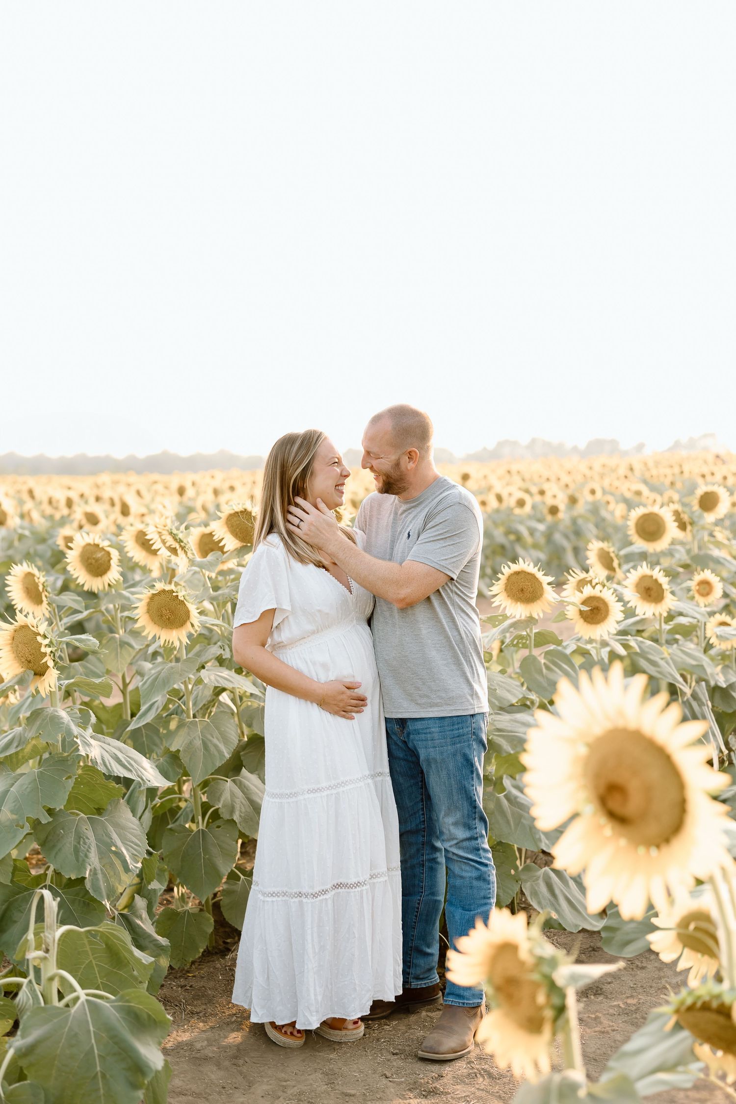 A romantic couple shares tender moments in a golden sunflower field during sunset.