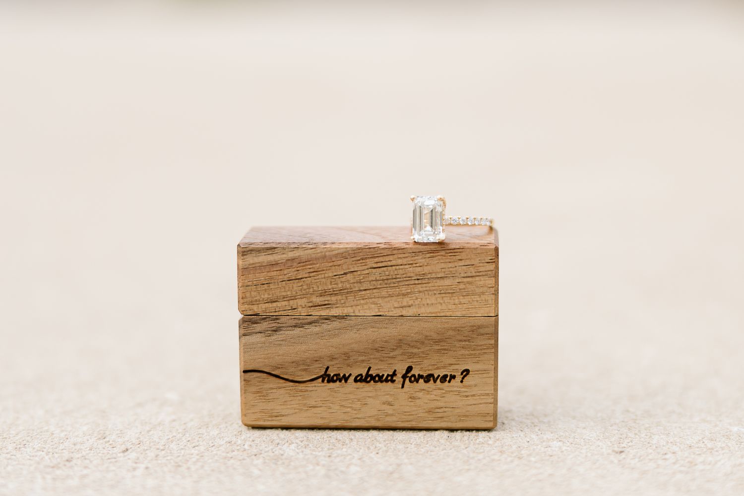 Wooden block with text 'love above forever' engraved in cursive script on a light background.