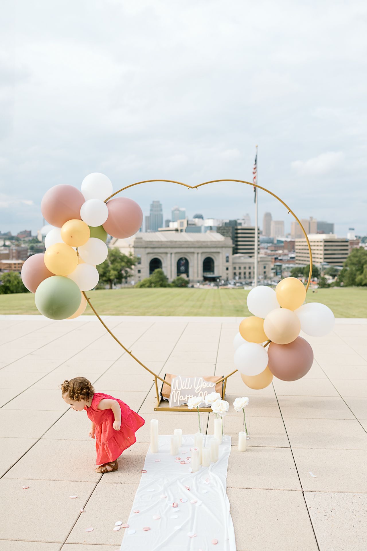 Elegant balloon arch setup with neutral colors on a rooftop terrace overlooking a cityscape with Union Station in background.