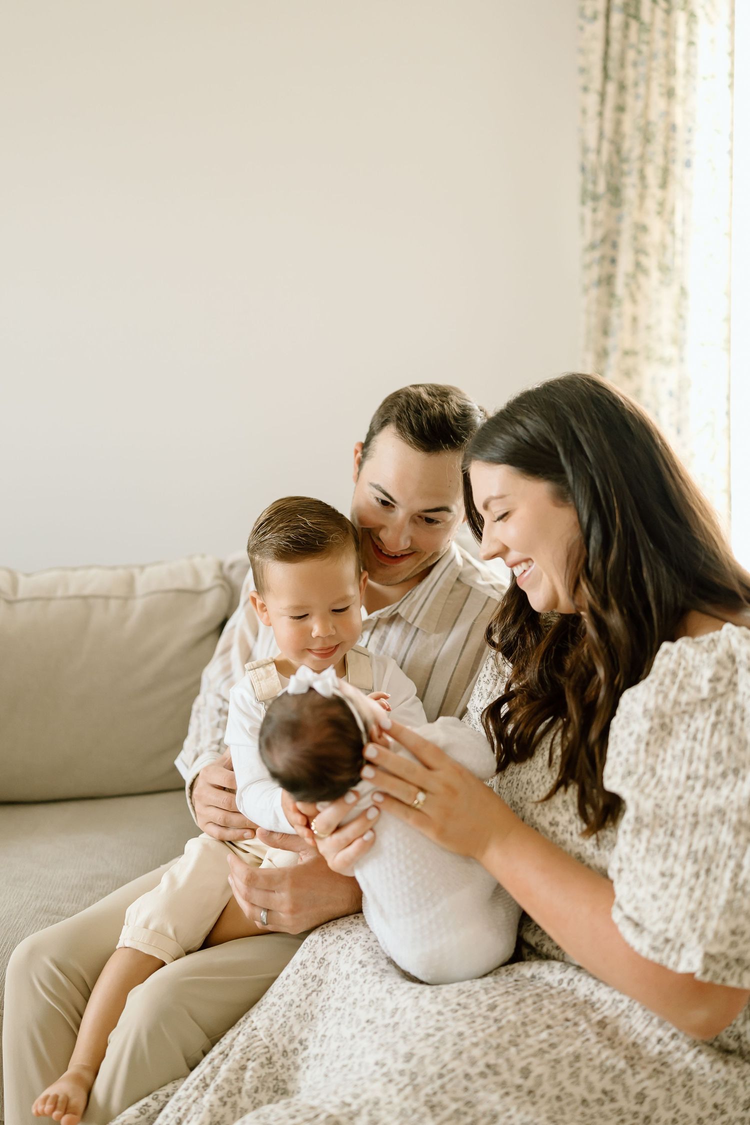 A loving family shares tender moments with their newborn baby in a series of intimate photos on a light colored couch.