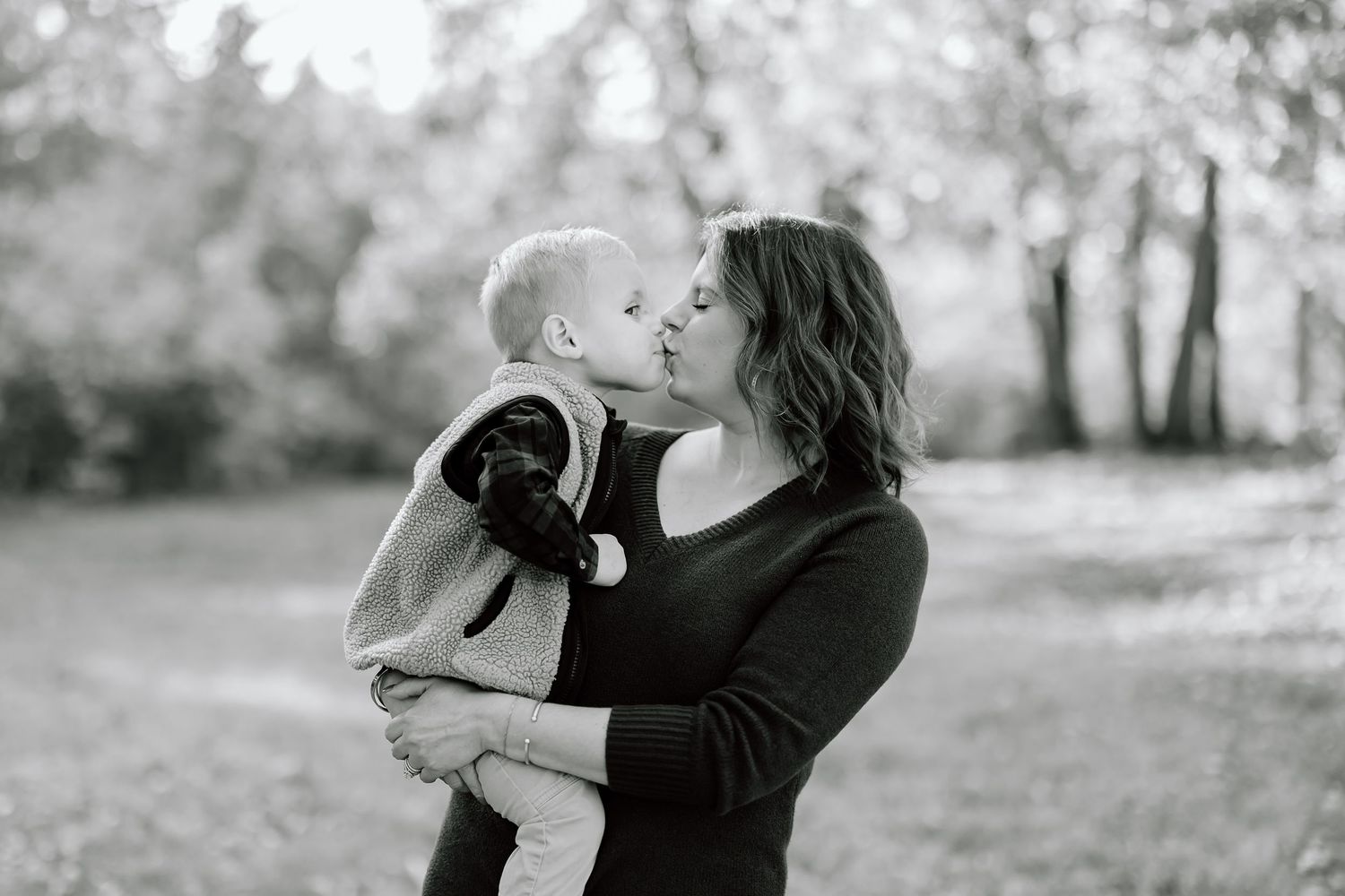A black and white photo captures a tender moment between parent and child outdoors.